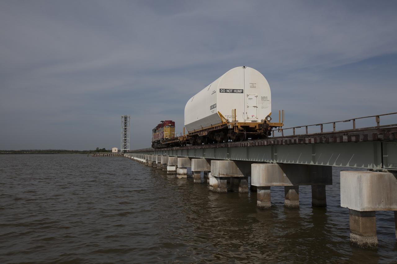 An Iowa Northern locomotive, conracted by Goodloe Transportation of Chicago, travels along the NASA railroad bridge over the Indian River north of Kennedy Space Center, with two containers on railcars for transport to the NASA Jay Jay railroad yard. The containers held two pathfinders, or test versions, of solid rocket booster segments for NASA’s Space Launch System rocket that were delivered to the Rotation, Processing and Surge Facility (RPSF). Inside the RPSF, the Ground Systems Development and Operations Program and Jacobs Engineering, on the Test and Operations Support Contract, will conduct a series of lifts, moves and stacking operations using the booster segments, which are inert, to prepare for Exploration Mission-1, deep-space missions and the journey to Mars. The pathfinder booster segments are from Orbital ATK in Utah. 