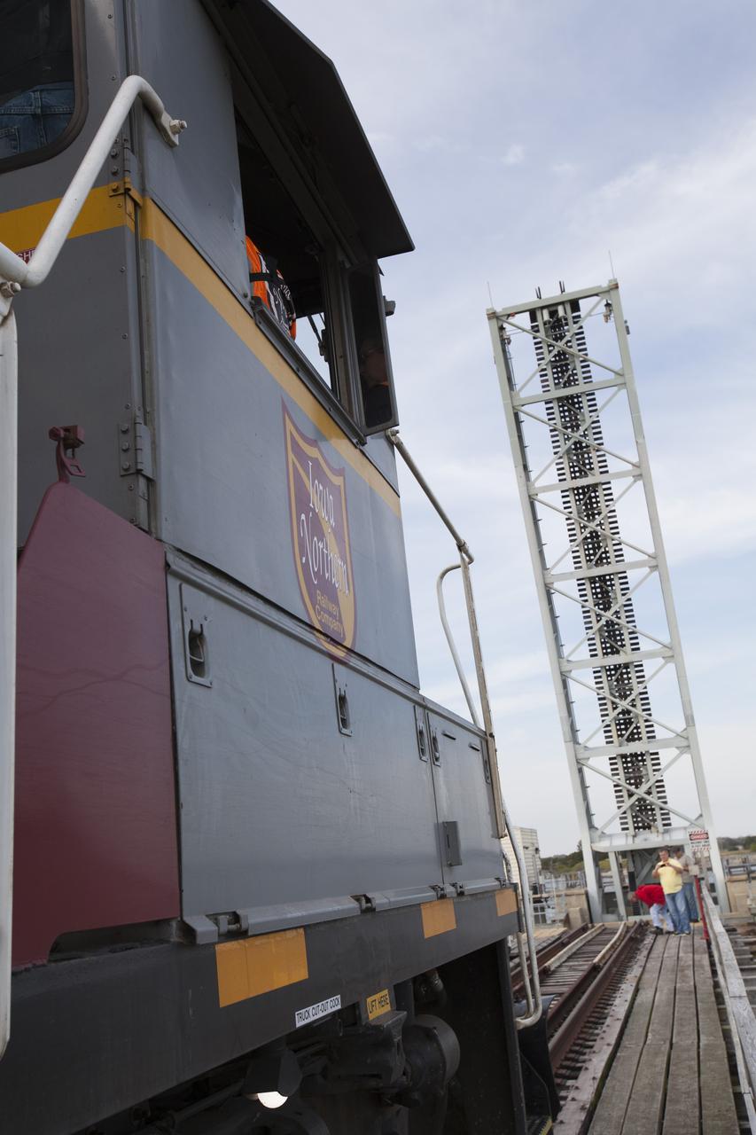 An Iowa Northern locomotive, contracted by Goodloe Transportation of Chicago, approaches the raised span of the NASA railroad bridge to continue over the Indian River north of Kennedy Space Center with two containers on railcars for storage at the NASA Jay Jay railroad yard. The containers held two pathfinders, or test versions, of solid rocket booster segments for NASA’s Space Launch System rocket that were delivered to the Rotation, Processing and Surge Facility (RPSF). Inside the RPSF, the Ground Systems Development and Operations Program and Jacobs Engineering, on the Test and Operations Support Contract, will conduct a series of lifts, moves and stacking operations using the booster segments, which are inert, to prepare for Exploration Mission-1, deep-space missions and the journey to Mars. The pathfinder booster segments are from Orbital ATK in Utah. 