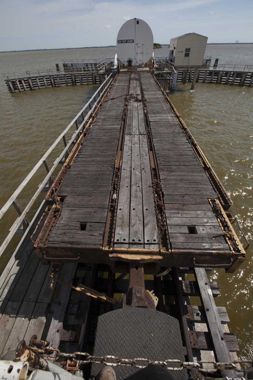 An Iowa Northern locomotive, contracted by Goodloe Transportation of Chicago, continues along the NASA railroad bridge over the Indian River north of Kennedy Space Center, carrying one of two containers on a railcar for transport to the NASA Jay Jay railroad yard. The containers held two pathfinders, or test versions, of solid rocket booster segments for NASA’s Space Launch System rocket that were delivered to the Rotation, Processing and Surge Facility (RPSF). Inside the RPSF, the Ground Systems Development and Operations Program and Jacobs Engineering, on the Test and Operations Support Contract, will conduct a series of lifts, moves and stacking operations using the booster segments, which are inert, to prepare for Exploration Mission-1, deep-space missions and the journey to Mars. The pathfinder booster segments are from Orbital ATK in Utah. 