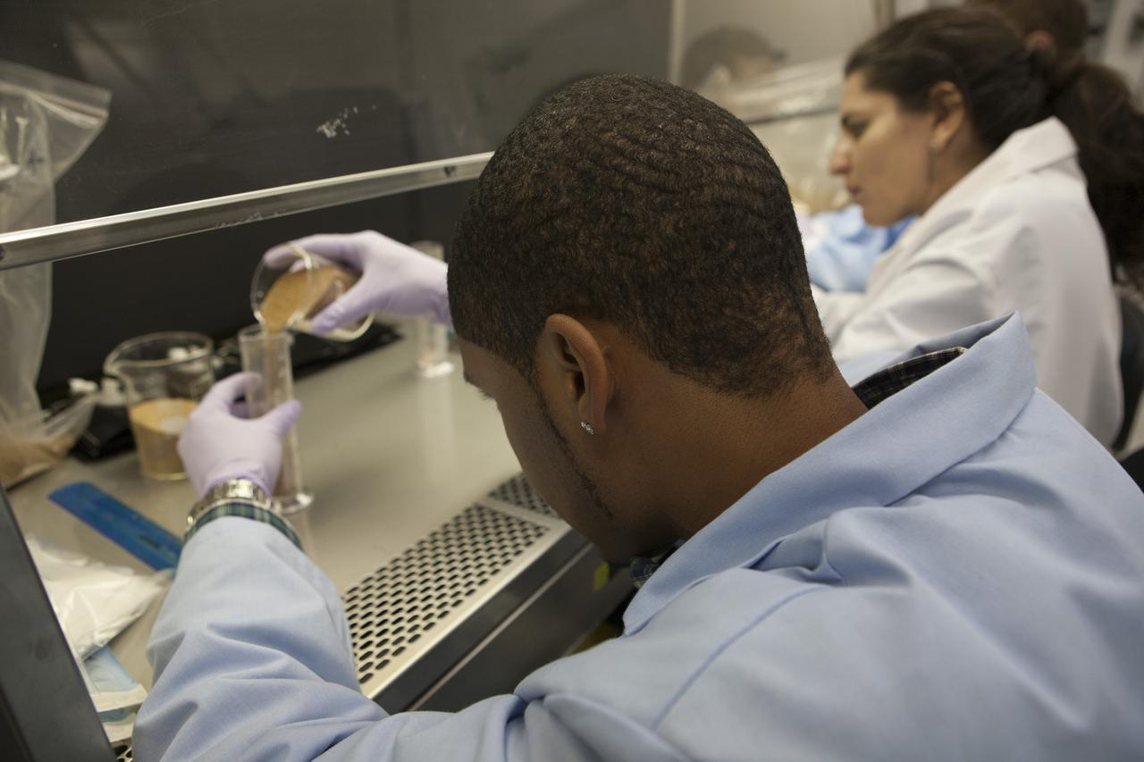 Inside a laboratory in the Space Station Processing Facility at NASA’s Kennedy Space Center in Florida, research scientists prepare the plant pillows for the Veg-03 experiment that will be delivered to the International Space Station aboard the eighth SpaceX Dragon commercial resupply mission. Matt Romeyn, a NASA pathways intern, measures out the calcined clay, or space dirt, for one of the plant pillows. To his right is Dr. Gioia Massa, NASA payload scientist for Veggie. The Veg-03 plant pillows will contain ‘Tokyo Bekana’ cabbage seeds and lettuce seeds for NASA’s third Veggie plant growth system experiment. The experiment will continue NASA’s deep space plant growth research to benefit the Earth and the agency’s journey to Mars.