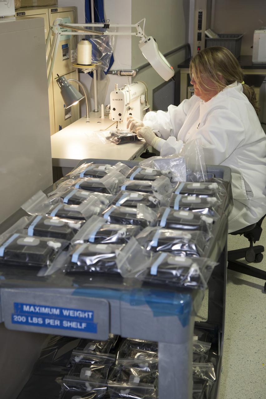 Inside a laboratory in the Space Station Processing Facility at NASA’s Kennedy Space Center in Florida, Michele Koralewicz, a mechanical technician with EASI on the Engineering Services Contract, prepares to sew up the end of a bag that contains one of the Veg-03 plant pillows. In the foreground are all of the other plant pillows that need to be sealed. The Veg-03 experiment will be delivered to the International Space Station aboard the eighth SpaceX Dragon commercial resupply mission. The Veg-03 plant pillows will contain ‘Tokyo Bekana’ cabbage seeds and lettuce seeds for NASA’s third Veggie plant growth system experiment. The experiment will continue NASA’s deep space plant growth research to benefit the Earth and the agency’s journey to Mars.