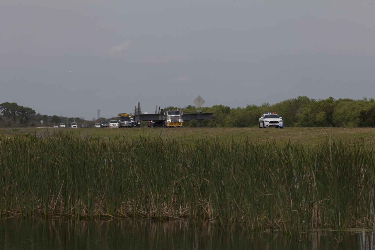 A heavy load transport truck passes through the north entrance gate at NASA’s Kennedy Space Center in Florida, carrying the second half of the F-level work platforms for the agency’s Space Launch System (SLS) rocket. The platform will be delivered to the Vehicle Assembly Building (VAB) staging area in the west parking lot. The Ground Systems Development and Operations Program is overseeing upgrades and modifications to VAB High Bay 3 to support processing of the SLS and Orion spacecraft. A total of 10 levels of new platforms, 20 platform halves altogether, will surround the SLS rocket and Orion spacecraft and provide access for testing and processing. Delivery of this platform brings the total to 10 platforms, or half of the work platforms delivered to Kennedy. 