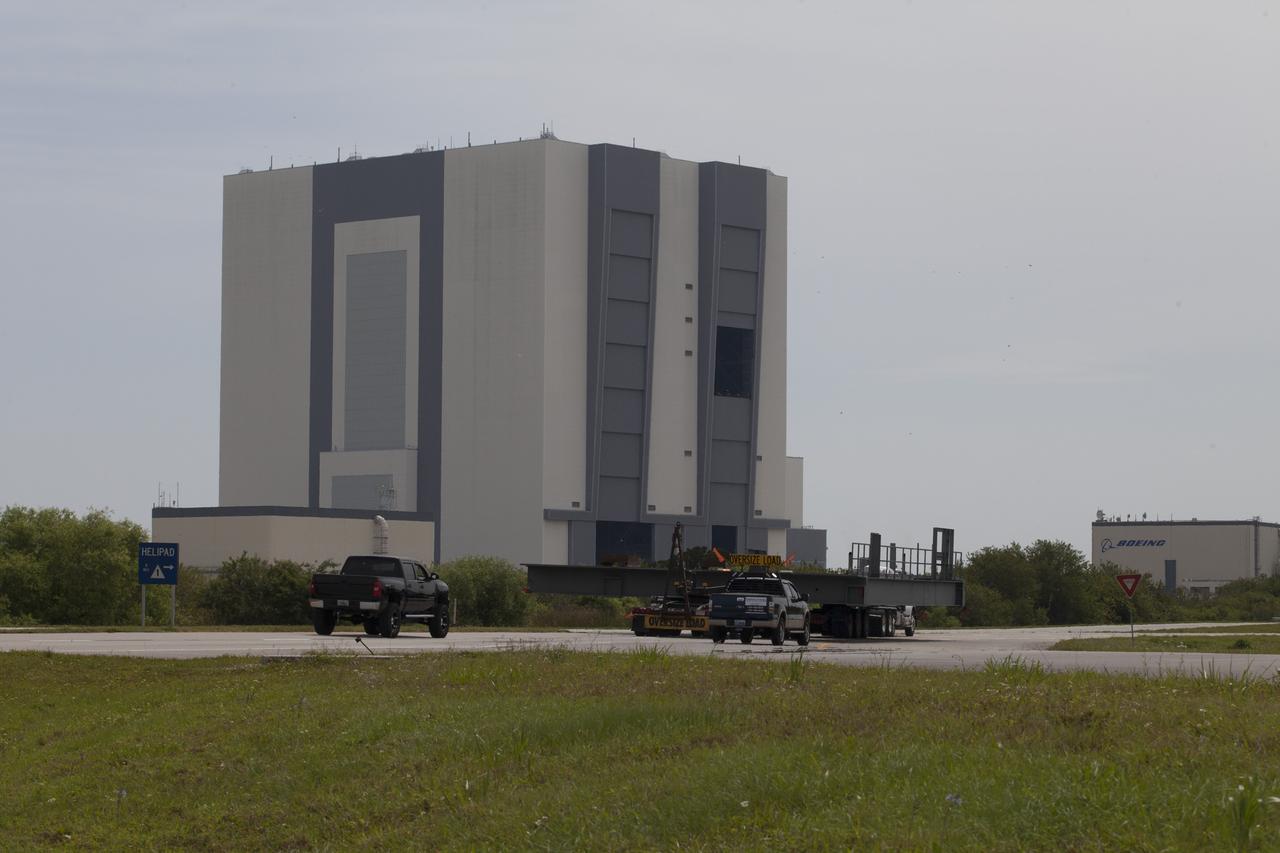 A heavy load transport truck proceeds along the road toward the Vehicle Assembly Building (VAB) at NASA’s Kennedy Space Center in Florida, carrying the second half of the F-level work platforms for the agency’s Space Launch System (SLS) rocket. The platform will be delivered to the VAB staging area in the west parking lot. The Ground Systems Development and Operations Program is overseeing upgrades and modifications to VAB High Bay 3 to support processing of the SLS and Orion spacecraft. A total of 10 levels of new platforms, 20 platform halves altogether, will surround the SLS rocket and Orion spacecraft and provide access for testing and processing. Delivery of this platform brings the total to 10 platforms, or half of the work platforms delivered to Kennedy. 