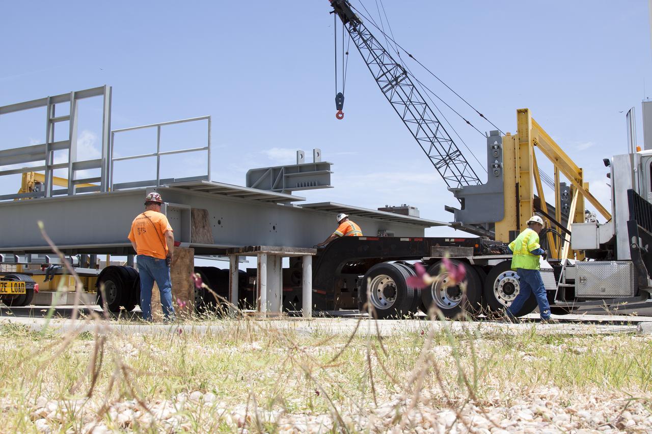 A heavy load transport truck from Tillett Heavy Hauling in Titusville, Florida, arrives at the Vehicle Assembly Building (VAB) at NASA’s Kennedy Space Center in Florida, carrying a section of the first half of the C-level work platforms, C South, for the agency’s Space Launch System (SLS) rocket. The platform is being lifted and transferred onto support stands in the VAB staging area in the west parking lot. The Ground Systems Development and Operations Program is overseeing upgrades and modifications to VAB High Bay 3 to support processing of the SLS and Orion spacecraft. A total of 10 levels of new platforms, 20 platform halves altogether, will surround the SLS rocket and Orion spacecraft and provide access for testing and processing. 