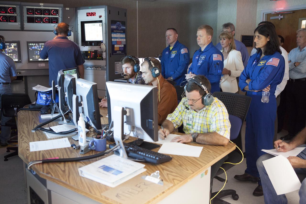 NASA astronauts Barry "Butch" Wilmore, from left, Eric Boe and Suni Williams watch as Aerojet Rocketdyne test team engineers direct the test-firing of an RL10 engine at the company's facility in West Palm Beach, Florida. The engine will be one of two used for the Centaur upper stage during a United Launch Alliance Atlas V mission to launch Boeing's CST-100 Starliner on a flight test carrying a crew. The engine was test-fired as part of acceptance testing to confirm the engine is ready for flight. 