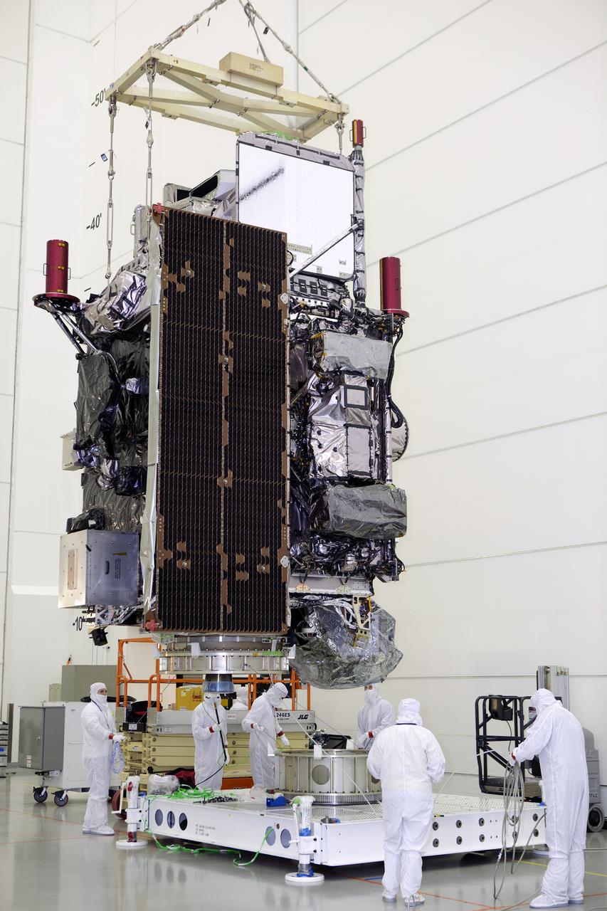 Team members monitor progress as an overhead crane lowers the GOES-R spacecraft toward its work stand inside the Astrotech payload processing facility in Titusville, Florida near NASA’s Kennedy Space Center. GOES-R will be the first satellite in a series of next-generation NOAA Geostationary Operational Environmental Satellites. The spacecraft is to launch aboard a United Launch Alliance Atlas V rocket in November.