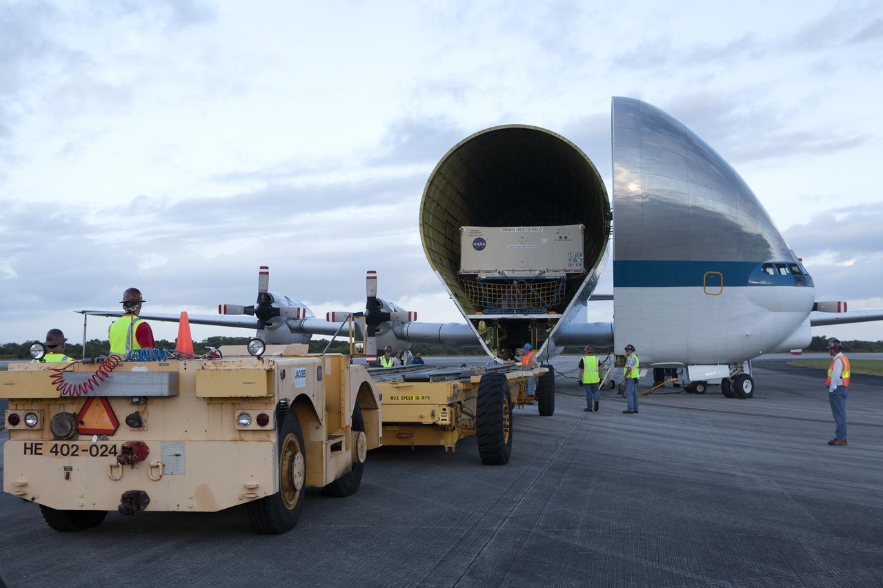 Technicians with Jacobs on the Test and Operations Support Contract move a transporter close to NASA’s Super Guppy aircraft at the Shuttle Landing Facility, managed and operated by Space Florida, at the agency’s Kennedy Space Center in Florida. The shipping container carrying the Orion heat shield for Exploration Mission 1 will be offloaded and delivered to the Neil Armstrong Operations and Checkout Building high bay for processing. The heat shield arrived from Lockheed Martin’s manufacturing facility near Denver. The Orion spacecraft will launch atop NASA’s Space Launch System rocket on EM-1, an uncrewed test flight, in 2018. 