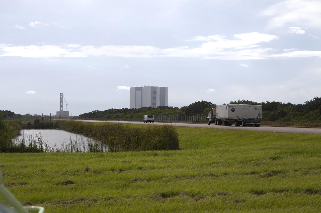 The shipping container carrying the Orion heat shield for Exploration Mission 1 (EM-1) is transported by truck from the Shuttle Landing Facility at NASA’s Kennedy Space Center in Florida along the road to the Neil Armstrong Operations and Checkout Building high bay for processing. The heat shield arrived aboard the agency’s Super Guppy aircraft, managed and operated by Space Florida, from Lockheed Martin’s manufacturing facility near Denver. The Orion spacecraft will launch atop NASA’s Space Launch System rocket on EM-1, an uncrewed test flight, in 2018. 