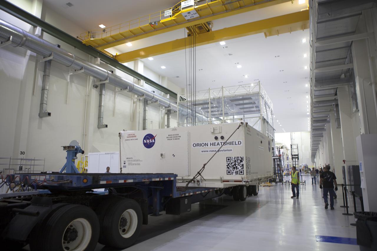 A flatbed truck with the shipping container carrying the Orion heat shield for Exploration Mission 1 (EM-1) backs into the low bay at the Neil Armstrong Operations and Checkout Building at NASA’s Kennedy Space Center in Florida. The heat shield arrived aboard the agency’s Super Guppy aircraft at the Shuttle Landing Facility, managed and operated by Space Florida, from Lockheed Martin’s manufacturing facility near Denver. The heat shield will be offloaded and moved into the high bay for processing. The Orion spacecraft will launch atop NASA’s Space Launch System rocket on EM-1, an uncrewed test flight, in 2018. 