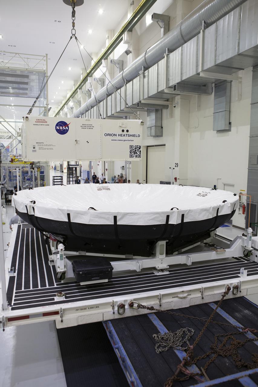 Inside the Neil Armstrong Operations and Checkout Building high bay at NASA’s Kennedy Space Center in Florida, a crane removes the top of the shipping container carrying the Orion heat shield for Exploration Mission 1 (EM-1) The heat shield arrived aboard the agency’s Super Guppy aircraft at the Shuttle Landing Facility, managed and operated by Space Florida, from Lockheed Martin’s manufacturing facility near Denver. The heat shield will be offloaded and moved into the high bay for processing. The Orion spacecraft will launch atop NASA’s Space Launch System rocket on EM-1, an uncrewed test flight, in 2018. 
