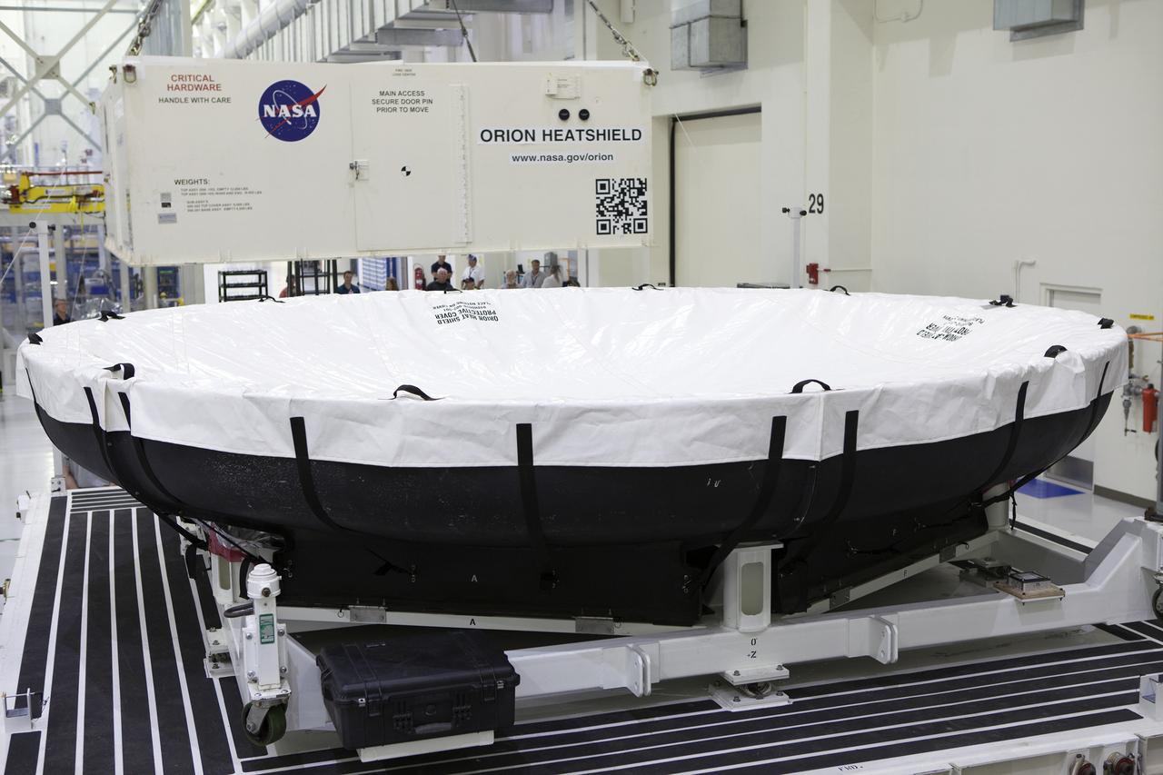 Inside the Neil Armstrong Operations and Checkout Building high bay at NASA’s Kennedy Space Center in Florida, a crane removes the top of the shipping container carrying the Orion heat shield for Exploration Mission 1 (EM-1). The heat shield arrived aboard the agency’s Super Guppy aircraft at the Shuttle Landing Facility, managed and operated by Space Florida, from Lockheed Martin’s manufacturing facility near Denver. The heat shield will be offloaded and moved into the high bay for processing. The Orion spacecraft will launch atop NASA’s Space Launch System rocket on EM-1, an uncrewed test flight, in 2018. 
