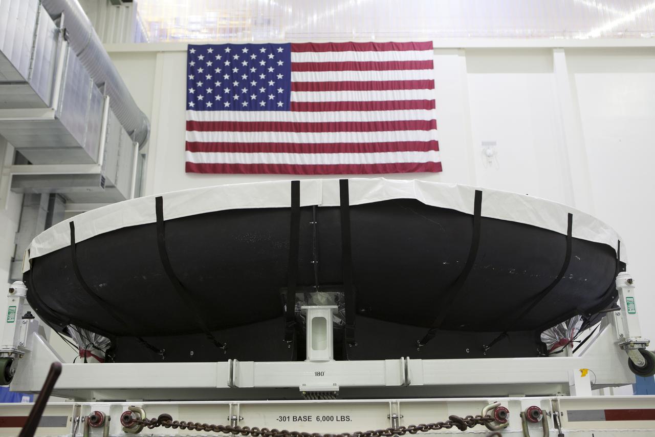 The American flag is in view above the Orion heat shield for Exploration Mission 1 (EM-1) inside the Neil Armstrong Operations and Checkout Building high bay at NASA’s Kennedy Space Center in Florida. The heat shield arrived aboard the agency’s Super Guppy aircraft at the Shuttle Landing Facility, managed and operated by Space Florida, from Lockheed Martin’s manufacturing facility near Denver. The heat shield will be offloaded and moved onto a test stand to begin processing. The Orion spacecraft will launch atop NASA’s Space Launch System rocket on EM-1, an uncrewed test flight, in 2018.