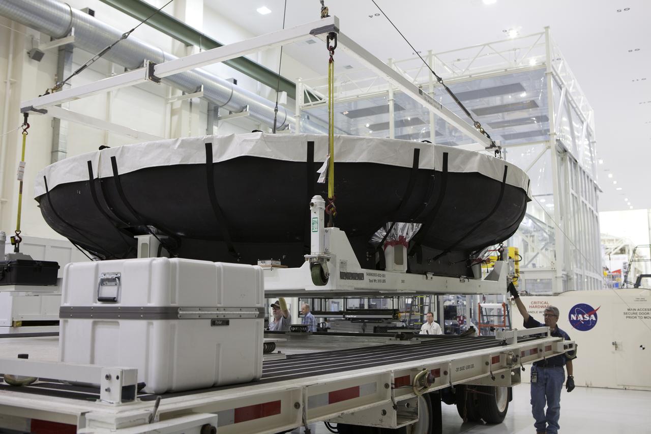 Inside the Neil Armstrong Operations and Checkout Building high bay at NASA’s Kennedy Space Center in Florida, a crane lifts the Orion heat shield for Exploration Mission 1 away from the base of its shipping container. The heat shield arrived aboard the agency’s Super Guppy aircraft at the Shuttle Landing Facility, managed and operated by Space Florida, from Lockheed Martin’s manufacturing facility near Denver. The heat shield will be moved onto a test stand to begin processing. The Orion spacecraft will launch atop NASA’s Space Launch System rocket on EM-1, an uncrewed test flight, in 2018. 