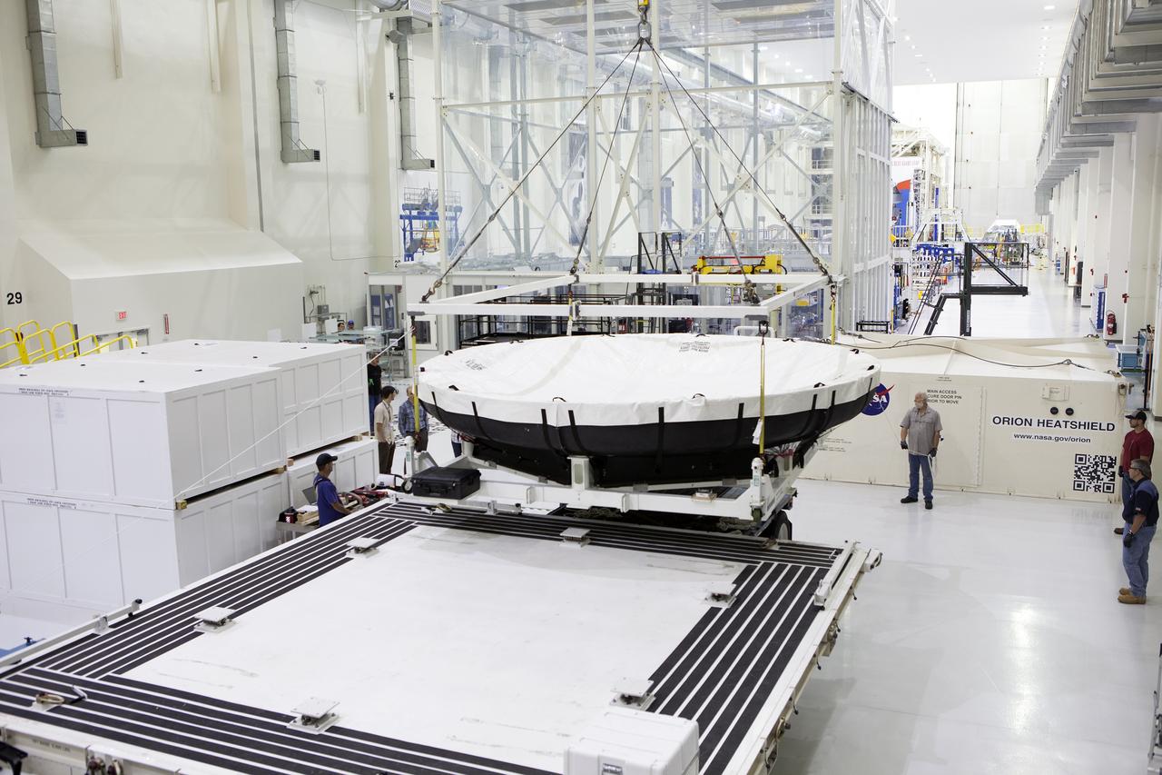 Inside the Neil Armstrong Operations and Checkout Building high bay at NASA’s Kennedy Space Center in Florida, a crane lifts the Orion heat shield for Exploration Mission 1 away from the base of its shipping container. The heat shield arrived aboard the agency’s Super Guppy aircraft at the Shuttle Landing Facility, managed and operated by Space Florida, from Lockheed Martin’s manufacturing facility near Denver. The heat shield will be moved onto a test stand to begin processing. The Orion spacecraft will launch atop NASA’s Space Launch System rocket on EM-1, an uncrewed test flight, in 2018. 