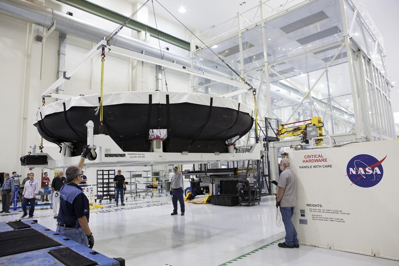 Inside the Neil Armstrong Operations and Checkout Building high bay at NASA’s Kennedy Space Center in Florida, technicians assist as a crane lifts the Orion heat shield for Exploration Mission 1 away from the base of its shipping container. The heat shield arrived aboard the agency’s Super Guppy aircraft at the Shuttle Landing Facility, managed and operated by Space Florida, from Lockheed Martin’s manufacturing facility near Denver. The heat shield will be moved onto a test stand to begin processing. The Orion spacecraft will launch atop NASA’s Space Launch System rocket on EM-1, an uncrewed test flight, in 2018. 