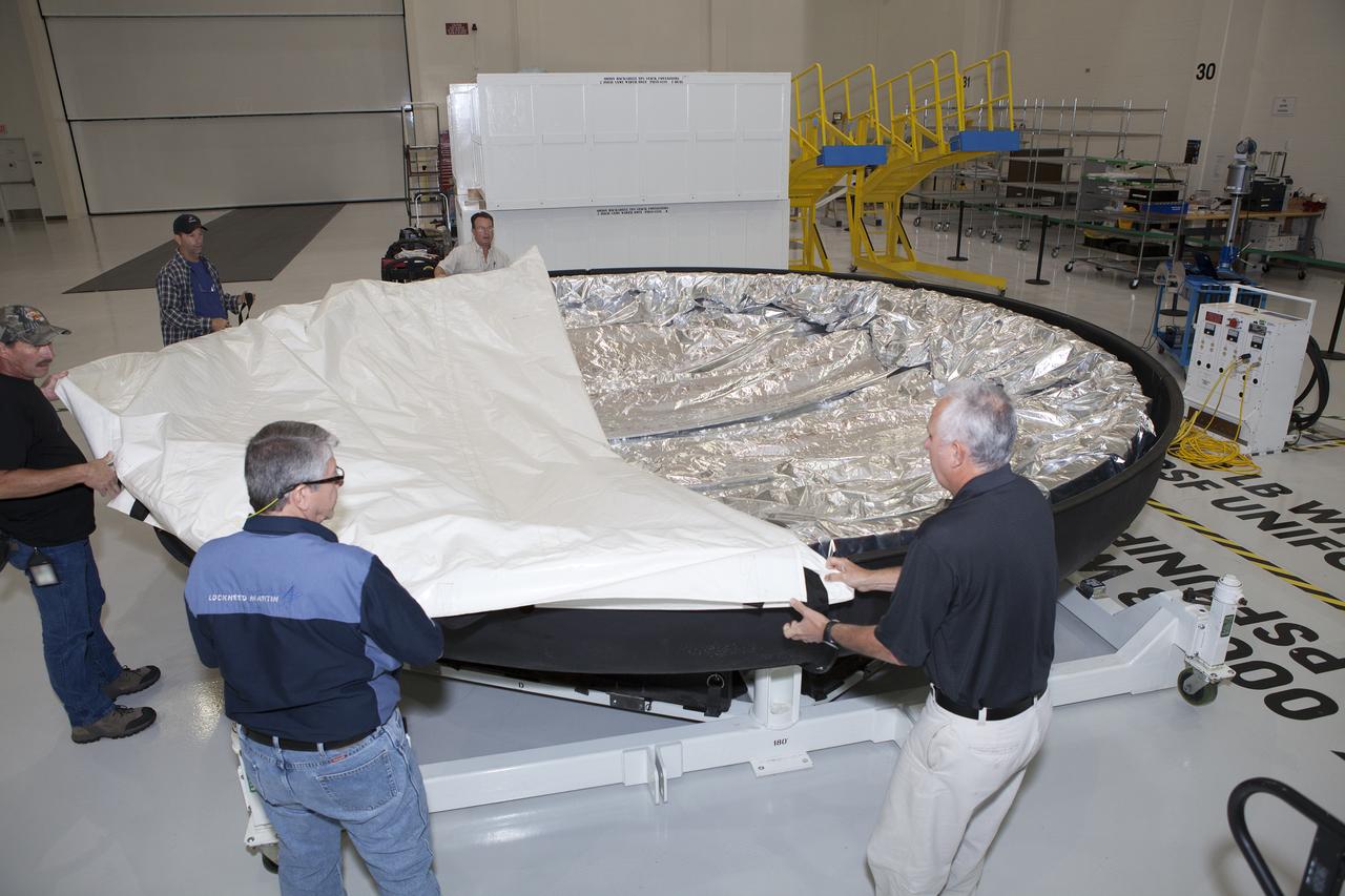 Inside the high bay in the Neil Armstrong Operations and Checkout Building at NASA’s Kennedy Space Center in Florida, technicians with Lockheed Martin start to remove the protective covering from the Orion heat shield for Exploration Mission 1 (EM-1). The heat shield arrived aboard NASA’s Super Guppy aircraft at the Shuttle Landing Facility, managed and operated by Space Florida, from Lockheed Martin’s manufacturing facility near Denver. The Orion spacecraft will launch atop NASA’s Space Launch System rocket on EM-1, an uncrewed test flight, targeted for November 2018. 