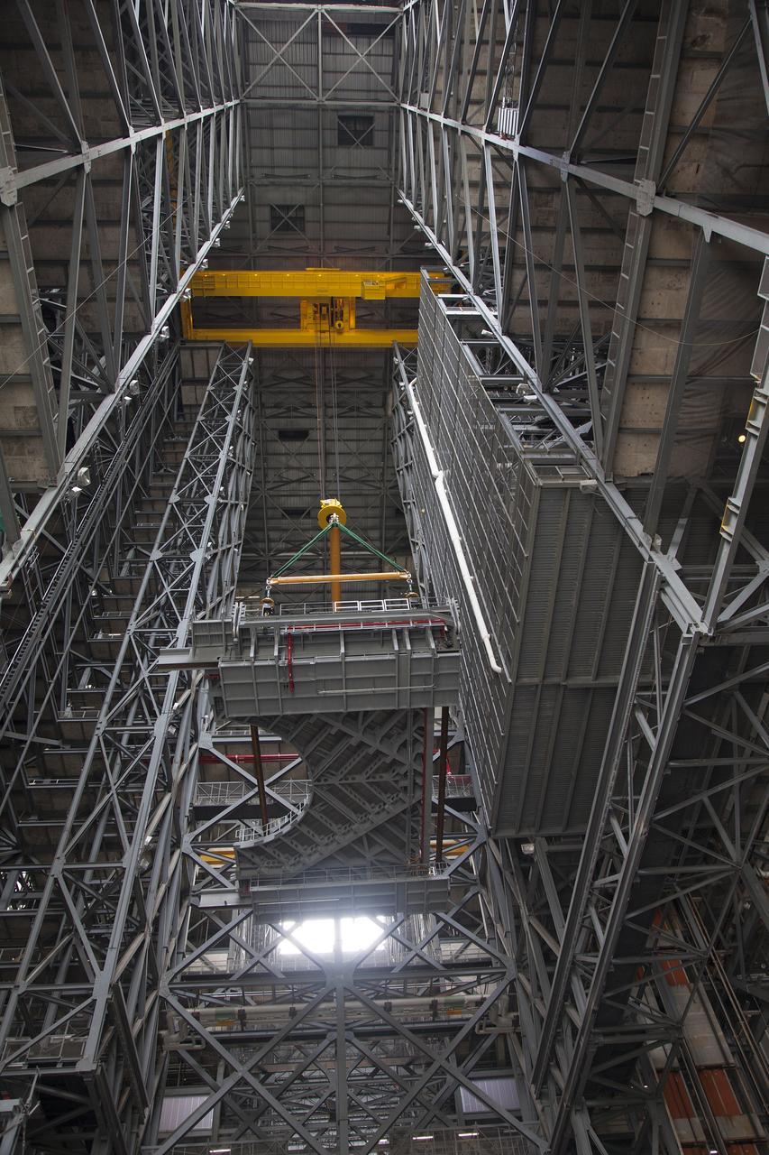 A heavy-lift crane lifts the first half of the E-level work platforms, E south, for NASA’s Space Launch System (SLS) rocket, high above the floor of the transfer aisle in the Vehicle Assembly Building (VAB) at NASA’s Kennedy Space Center in Florida. The E platform will be installed on the south side of High Bay 3, about 246 feet above the floor. The E platforms are the sixth of 10 levels of work platforms that will surround and provide access to the SLS rocket and Orion spacecraft for Exploration Mission 1. The Ground Systems Development and Operations Program is overseeing upgrades and modifications to VAB High Bay 3, including installation of the new work platforms, to prepare for NASA’s journey to Mars. 
