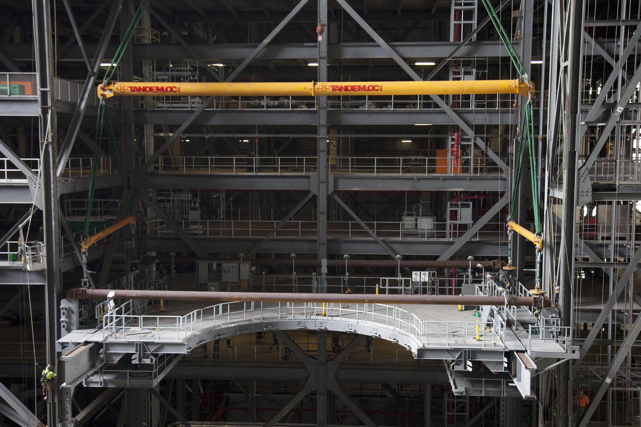 A heavy-lift crane lowers the first half of the E-level work platforms, E south, for NASA’s Space Launch System (SLS) rocket, into position for installation in High Bay 3 in the Vehicle Assembly Building (VAB) at NASA’s Kennedy Space Center in Florida. Large Tandemloc bars have been attached to the platform to keep it level during lifting and installation. The E platform will be installed on the south side of High Bay 3, about 246 feet above the floor. The E platforms are the sixth of 10 levels of work platforms that will surround and provide access to the SLS rocket and Orion spacecraft for Exploration Mission 1. The Ground Systems Development and Operations Program is overseeing upgrades and modifications to VAB High Bay 3, including installation of the new work platforms, to prepare for NASA’s journey to Mars. 
