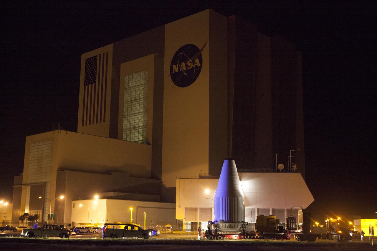 The OSIRIS-REx spacecraft, enclosed in a payload fairing, is towed past the Vehicle Assembly Building at NASA's Kennedy Space Center on its way to Space Launch Complex 41 at the adjacent Cape Canaveral Air Force Station. The United Launch Alliance Atlas V rocket that is to lift OSIRIS-REx into space was stacked at SLC-41 so the spacecraft and fairing could be hoisted and bolted to the rocket promptly. The spacecraft will be sent to rendezvous with, survey and take a sample from an asteroid called Bennu. 