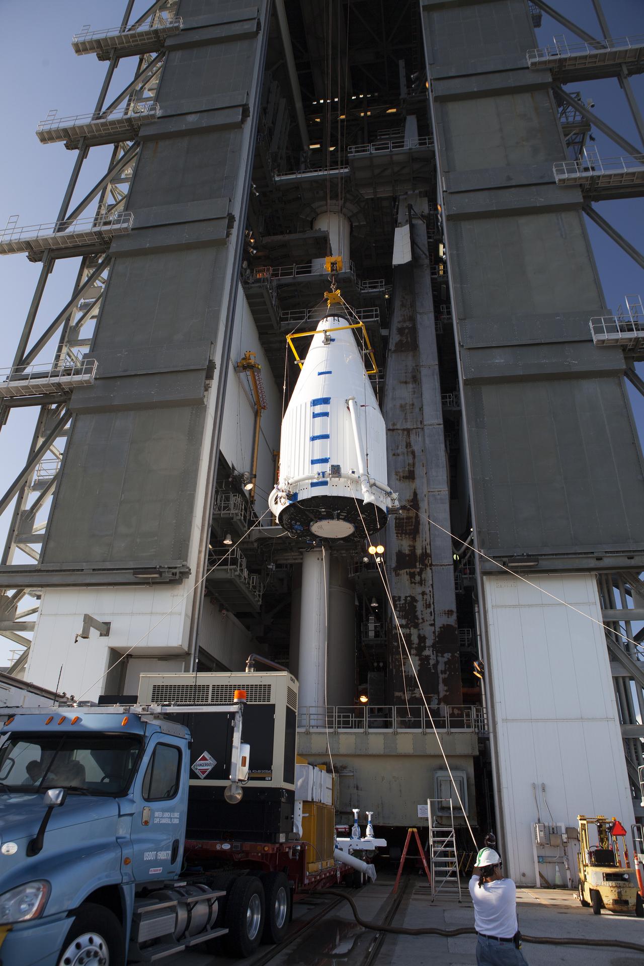 The rocket cone containing OSIRIS-REx being lifted to be stacked on the rocket. The rocket is tucked inside a tall building.