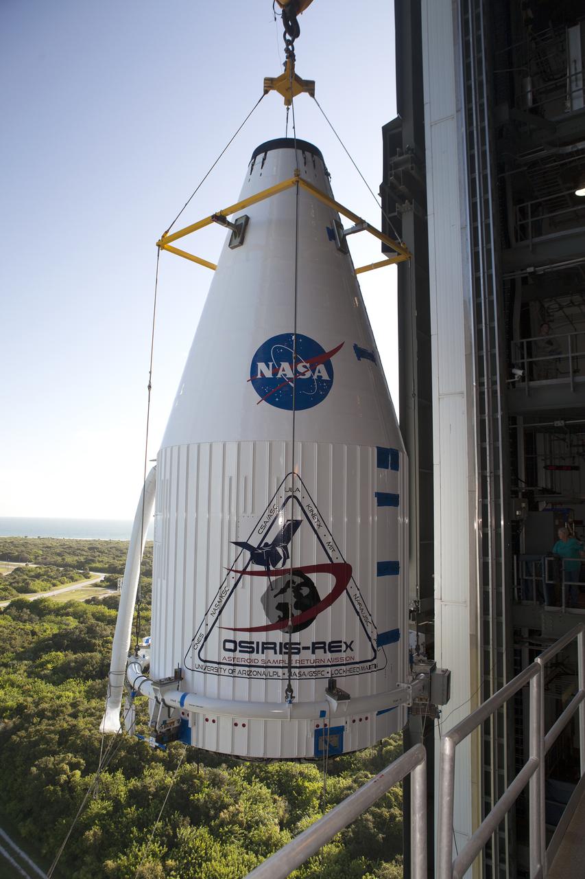 The OSIRIS-REx spacecraft, enclosed in a payload fairing, is lifted at Space Launch Complex 41 at Cape Canaveral Air Force Station. The United Launch Alliance Atlas V rocket that is to lift OSIRIS-REx into space was stacked at SLC-41 so the spacecraft and fairing could be hoisted and bolted to the rocket promptly. The spacecraft will be sent to rendezvous with, survey and take a sample from an asteroid called Bennu.