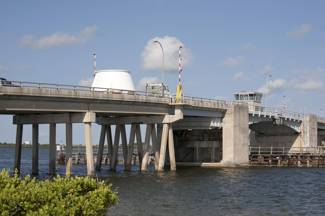 The left hand aft skirt for NASA’s Space Launch System (SLS) rocket is transported across the Roy D. Bridges Bridge from the Hangar AF facility at Cape Canaveral Air Force Station in Florida, on its way to the Booster Fabrication Facility at the agency’s Kennedy Space Center. The space shuttle-era aft skirt, was inspected, resurfaced, primed and painted for use on the left hand booster of the SLS rocket for Exploration Mission 1 (EM-1). NASA is preparing for EM-1, deep-space missions, and the journey to Mars. 