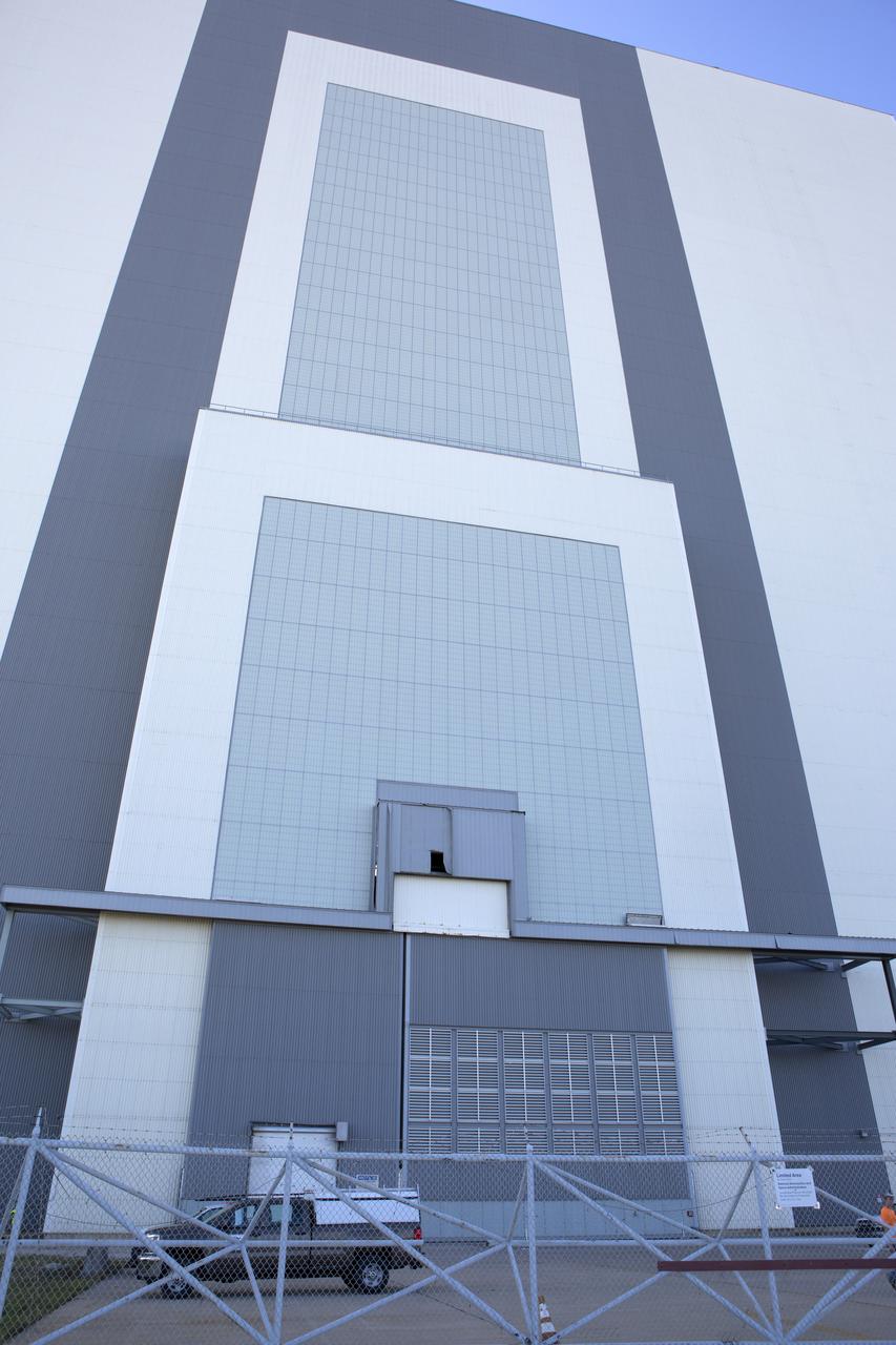 A hole caused by Hurricane Matthew is visible in a section of door on the Vehicle Assembly Building at NASA's Kennedy Space Center in Florida.  Assessments and repairs are in progress at various structures and facilities across the spaceport, part of the ongoing recovery from Hurricane Matthew, which passed to the east of Kennedy on Oct. 6 and 7, 2016. The center received some isolated roof damage, damaged support buildings, a few downed power lines, and limited water intrusion. Beach erosion also occurred, although the storm surge was less than expected.