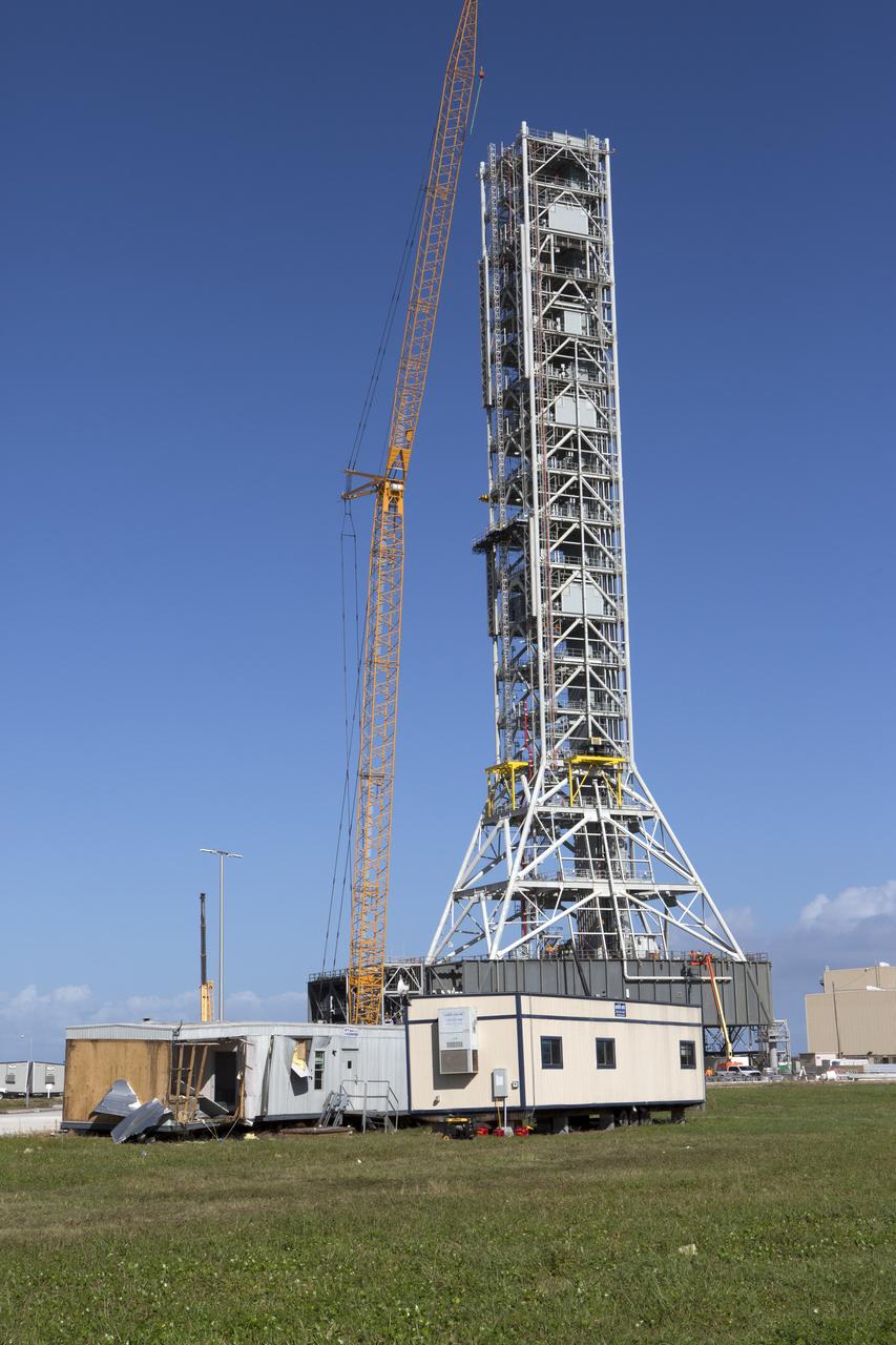 A construction trailer damaged by Hurricane Matthew is seen in front of the Mobile Launcher within the Launch Complex 39 area at NASA's Kennedy Space Center in Florida.  Assessments and repairs are in progress at various structures and facilities across the spaceport, part of the ongoing recovery from Hurricane Matthew, which passed to the east of Kennedy on Oct. 6 and 7, 2016. The center received some isolated roof damage, damaged support buildings, a few downed power lines, and limited water intrusion. Beach erosion also occurred, although the storm surge was less than expected.