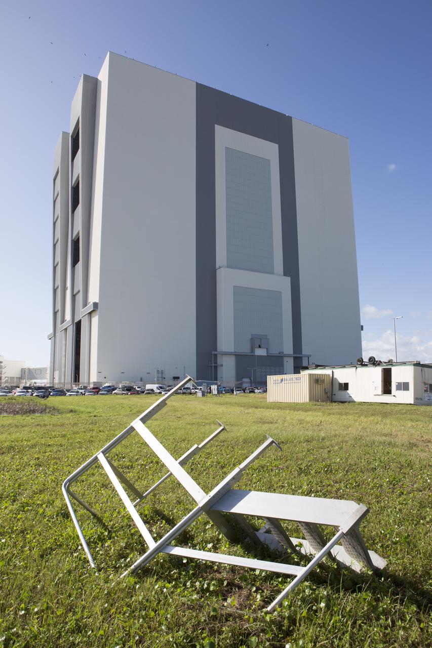 A small staircase, toppled and relocated by Hurricane Matthew, is seen in front of the Vehicle Assembly Building at NASA's Kennedy Space Center in Florida.  Assessments and repairs are in progress at various structures and facilities across the spaceport, part of the ongoing recovery from Hurricane Matthew, which passed to the east of Kennedy on Oct. 6 and 7, 2016. The center received some isolated roof damage, damaged support buildings, a few downed power lines, and limited water intrusion. Beach erosion also occurred, although the storm surge was less than expected.