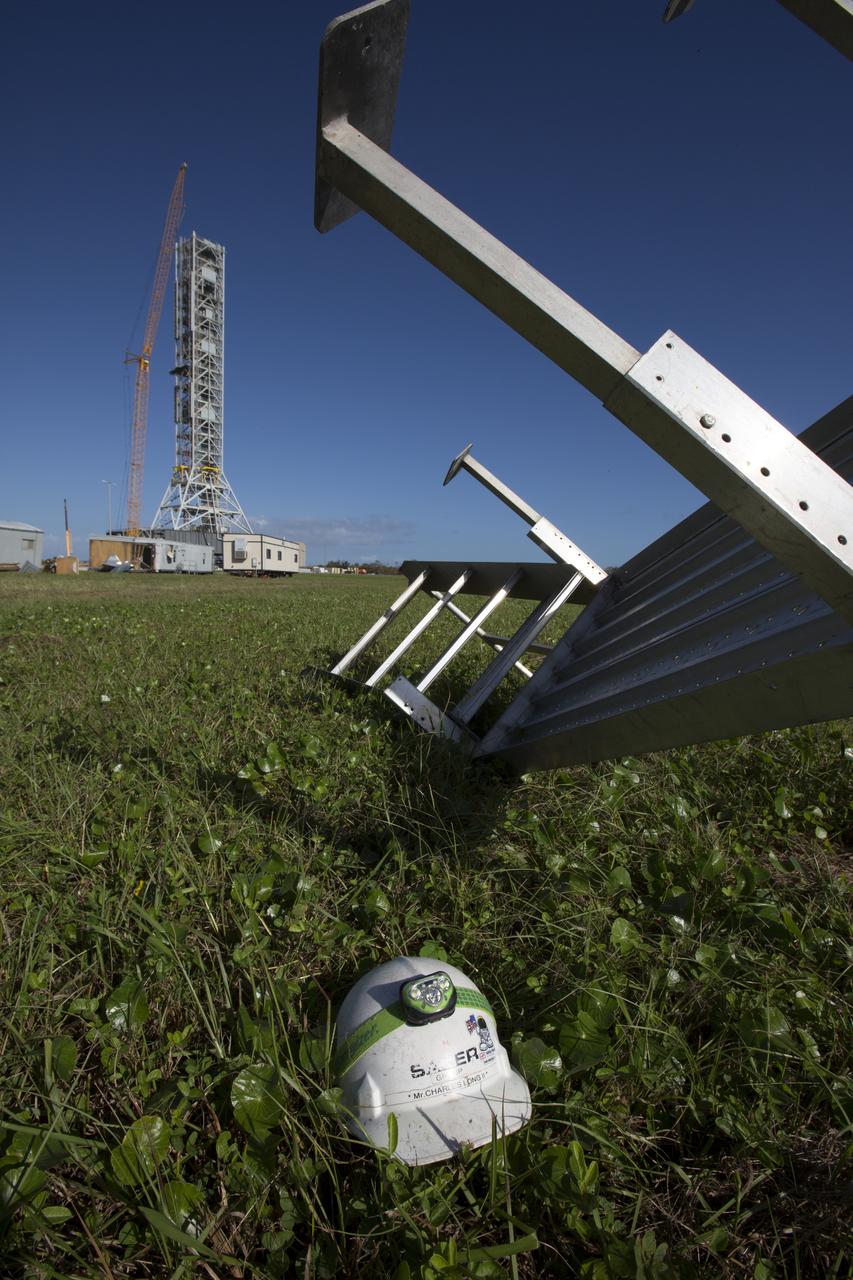 A construction helmet and staircase, both relocated by Hurricane Matthew, is seen in front of the Vehicle Assembly Building at NASA's Kennedy Space Center in Florida.  Assessments and repairs are in progress at various structures and facilities across the spaceport, part of the ongoing recovery from Hurricane Matthew, which passed to the east of Kennedy on Oct. 6 and 7, 2016. The center received some isolated roof damage, damaged support buildings, a few downed power lines, and limited water intrusion. Beach erosion also occurred, although the storm surge was less than expected.