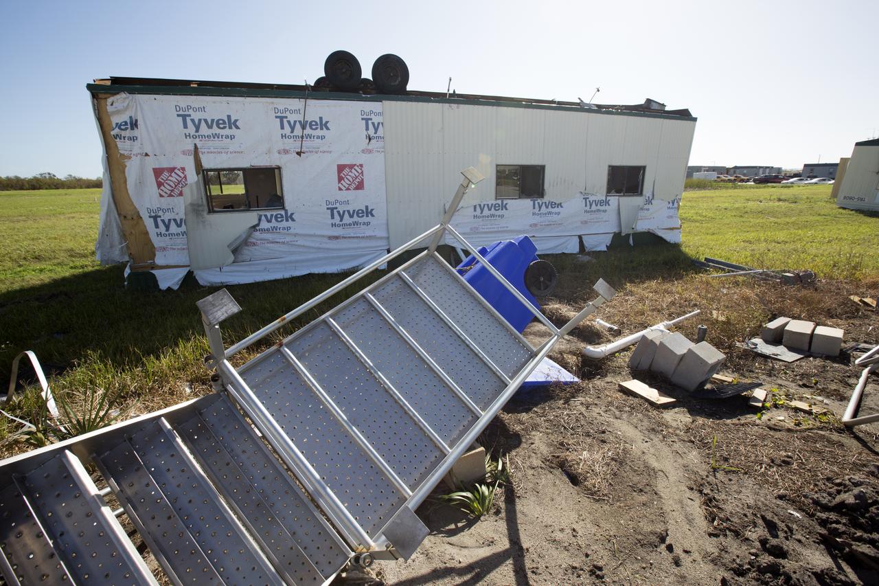 A damaged construction trailer and several pieces of associated debris, aftermath of Hurricane Matthew, are seen in front of the Mobile Launcher in the Launch Complex 39 area at NASA's Kennedy Space Center in Florida.  Assessments and repairs are in progress at various structures and facilities across the spaceport, part of the ongoing recovery from Hurricane Matthew, which passed to the east of Kennedy on Oct. 6 and 7, 2016. The center received some isolated roof damage, damaged support buildings, a few downed power lines, and limited water intrusion. Beach erosion also occurred, although the storm surge was less than expected.