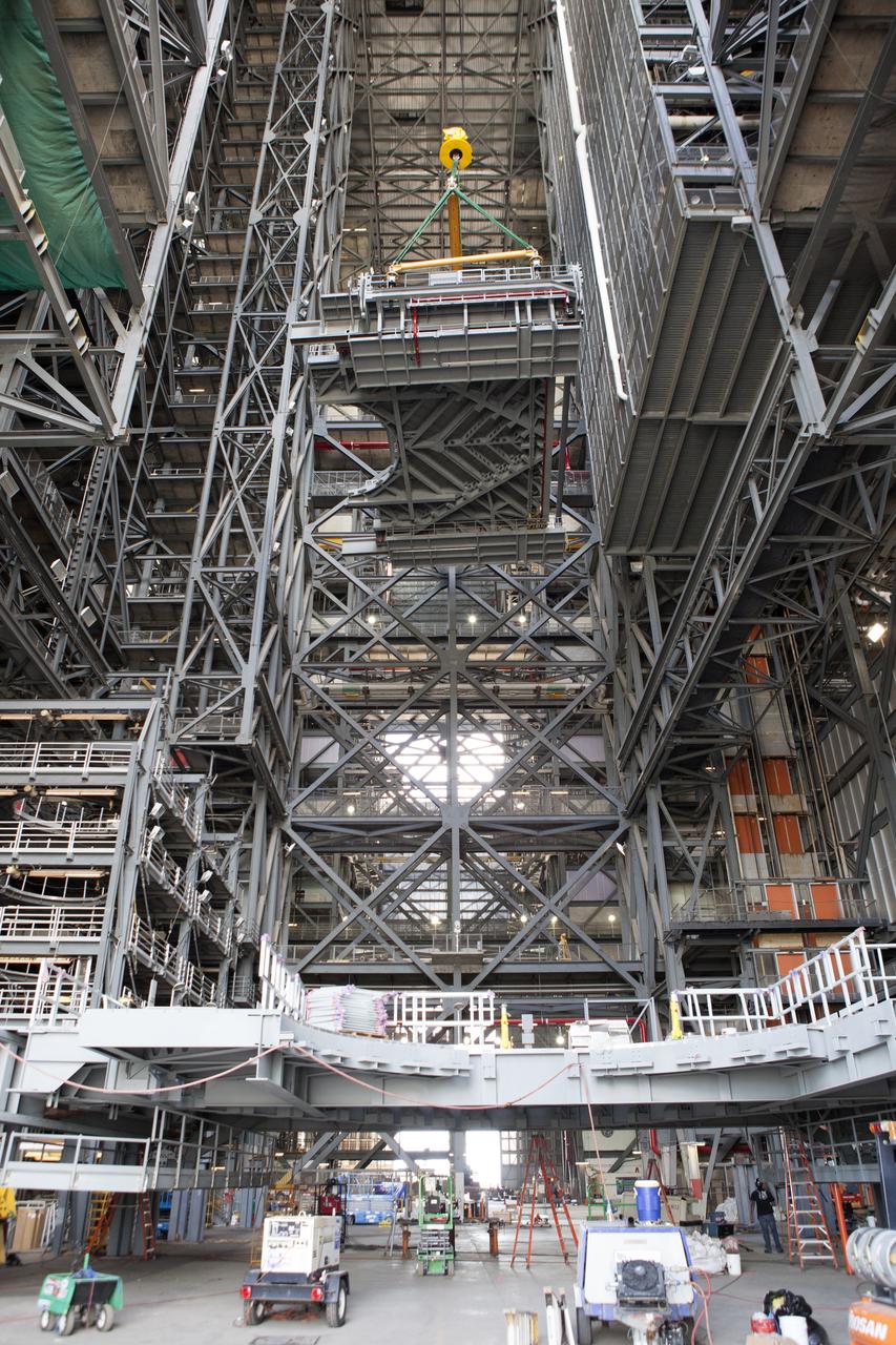 A heavy-lift crane lifts the first half of the C-level work platforms, C south, for NASA’s Space Launch System (SLS) rocket, high up from the transfer aisle floor of the Vehicle Assembly Building (VAB) at NASA’s Kennedy Space Center in Florida. The C platform will be installed on the south side of High Bay 3. The C platforms are the eighth of 10 levels of work platforms that will surround and provide access to the SLS rocket and Orion spacecraft for Exploration Mission 1. The Ground Systems Development and Operations Program is overseeing upgrades and modifications to VAB High Bay 3, including installation of the new work platforms, to prepare for NASA’s Journey to Mars.