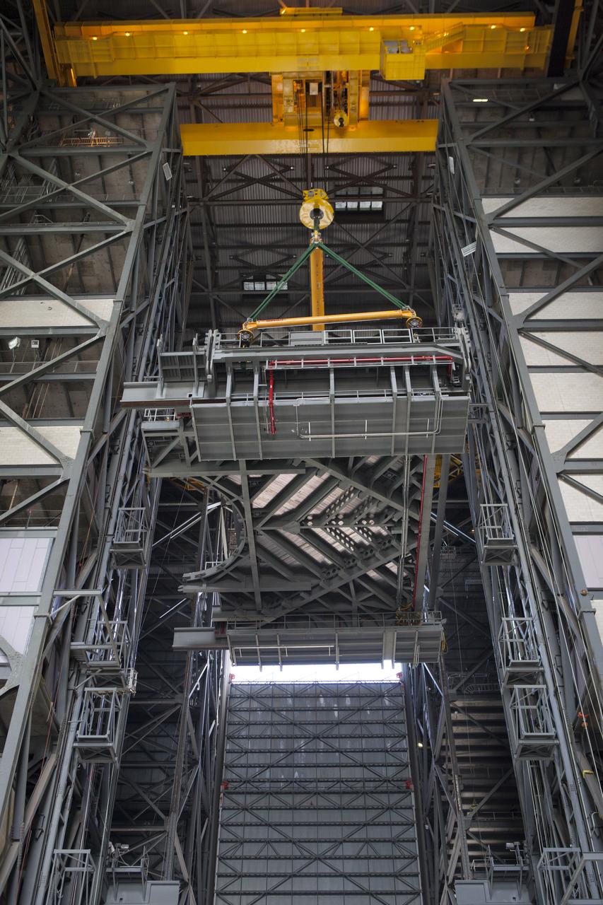 A heavy-lift crane lifts the first half of the C-level work platforms, C south, for NASA’s Space Launch System (SLS) rocket, high up from the transfer aisle floor of the Vehicle Assembly Building (VAB) at NASA’s Kennedy Space Center in Florida. The C platform will be moved into High Bay 3 for installation on the south wall. The C platforms are the eighth of 10 levels of work platforms that will surround and provide access to the SLS rocket and Orion spacecraft for Exploration Mission 1. The Ground Systems Development and Operations Program is overseeing upgrades and modifications to VAB High Bay 3, including installation of the new work platforms, to prepare for NASA’s Journey to Mars.