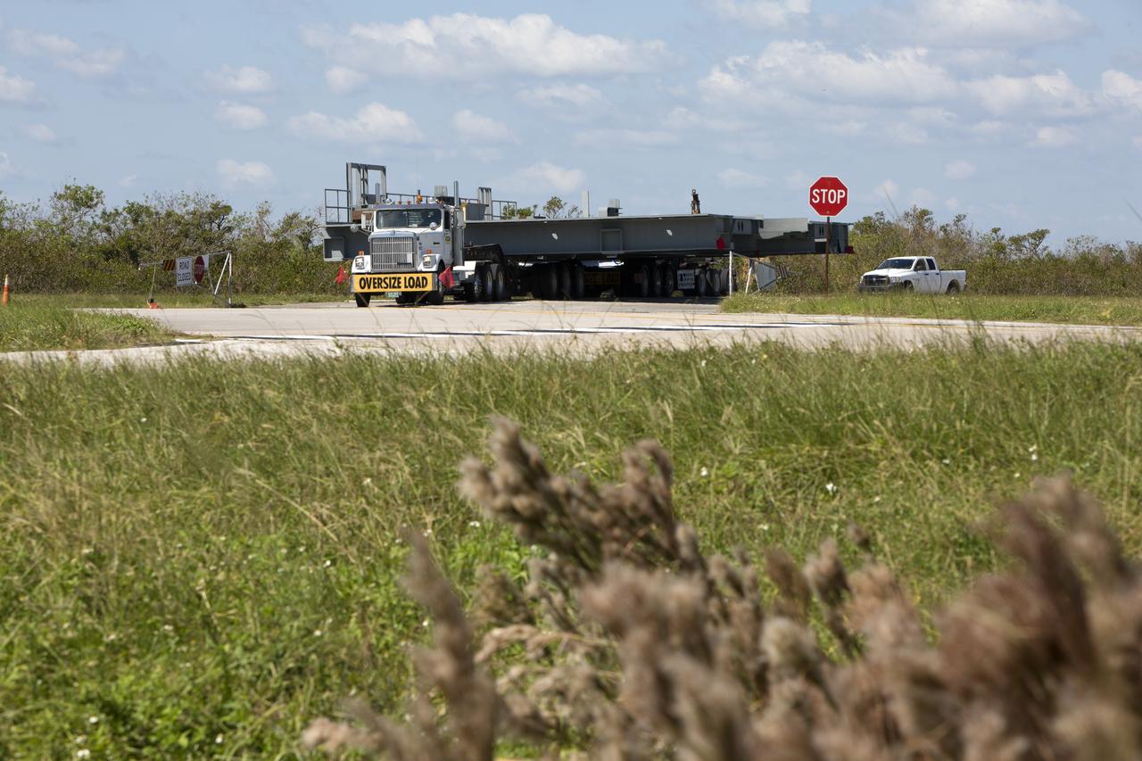 A heavy load transport truck from Tillett Heavy Hauling in Titusville, Florida, arrives at NASA’s Kennedy Space Center in Florida, carrying the first half of the B-level work platforms, B south, for the agency’s Space Launch System (SLS) rocket. The platform will be delivered to the Vehicle Assembly Building (VAB) staging area in the west parking lot. The Ground Systems Development and Operations Program is overseeing upgrades and modifications to VAB High Bay 3 to support processing of the SLS and Orion spacecraft. A total of 10 levels of new platforms, 20 platform halves altogether, will surround the SLS rocket and Orion spacecraft and provide access for testing and processing.