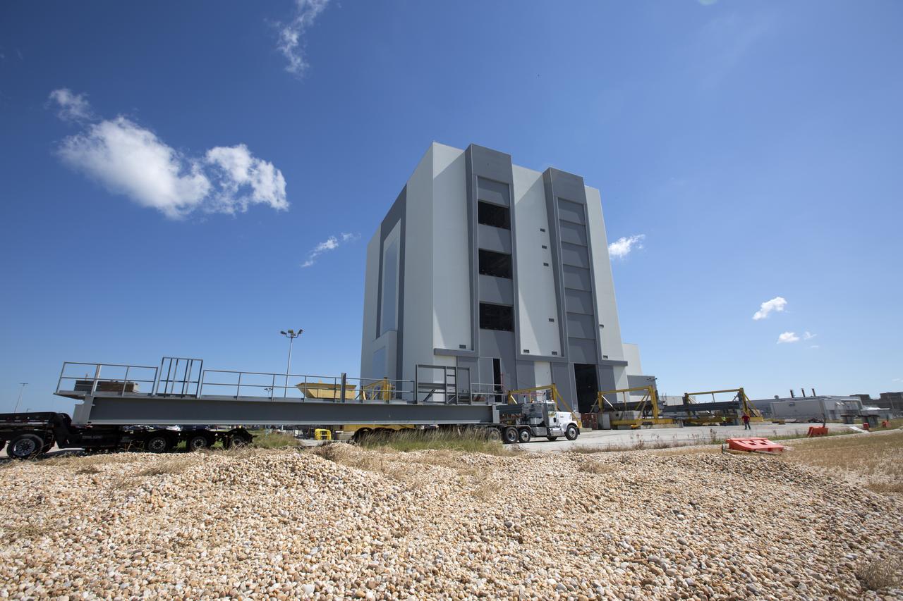 A heavy load transport truck from Tillett Heavy Hauling in Titusville, Florida, arrives at the Vehicle Assembly Building (VAB) at NASA’s Kennedy Space Center in Florida, carrying the first half of the B-level work platforms, B South, for the agency’s Space Launch System (SLS) rocket. The platform will be offloaded in the VAB staging area in the west parking lot. The Ground Systems Development and Operations Program is overseeing upgrades and modifications to VAB High Bay 3 to support processing of the SLS and Orion spacecraft. A total of 10 levels of new platforms, 20 platform halves altogether, will surround the SLS rocket and Orion spacecraft and provide access for testing and processing.