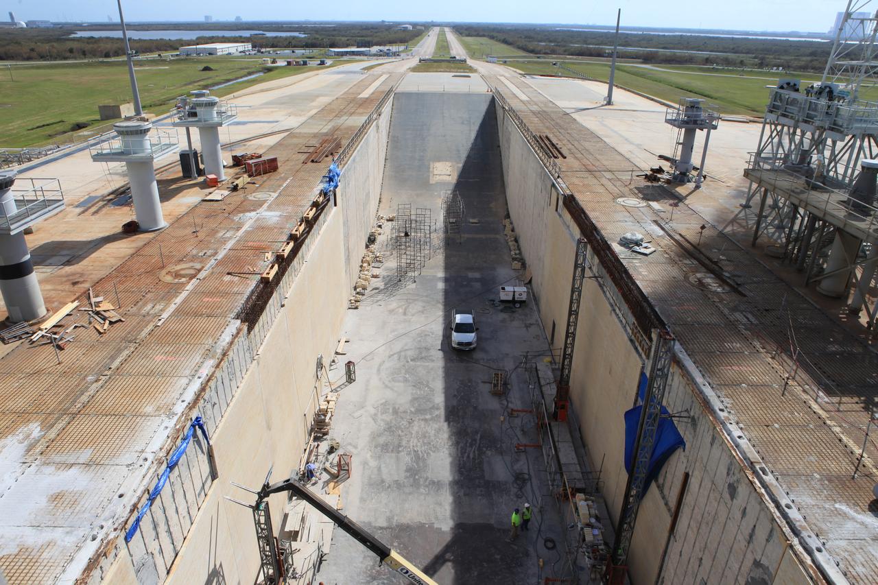 Progress on the new brick walls of the north side of the flame trench at Launch Pad 39B is seen in a view from the top of the pad at NASA’s Kennedy Space Center in Florida. Construction workers with J.P. Donovan of Rockledge, Florida, continue to install new heat-resistant bricks on the concrete walls. The Pad B flame trench is being refurbished to support the launch of NASA’s Space Launch System rocket. The Ground Systems Development and Operations (GSDO) Program at Kennedy is helping transform the space center into a multi-user spaceport and prepare for Exploration Mission 1, deep-space missions, and the journey to Mars. For more information about GSDO, visit: http://www.nasa.gov/groundsystems. 