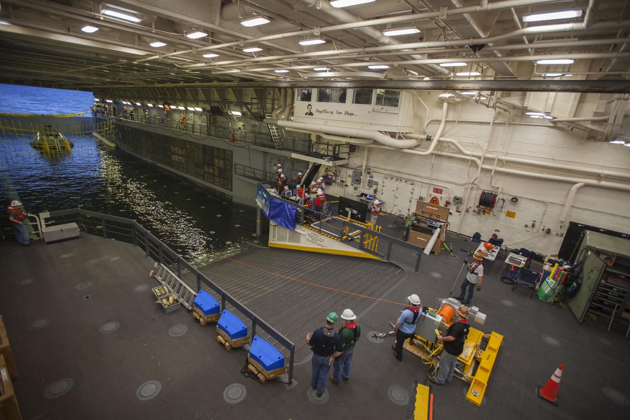 A test version of the Orion crew module attached to tether lines sits in the flooded well deck of the USS San Diego during Underway Recovery Test 5 in the Pacific Ocean off the coast of California. NASA's Ground Systems Development and Operations Program and the U.S. Navy are conducting a series of tests to prepare for recovery of Orion on its return from deep space missions. The testing will allow the team to demonstrate and evaluate recovery processes, procedures, hardware and personnel in open waters. Orion is the exploration spacecraft designed to carry astronauts to destinations not yet explored by humans, including an asteroid and NASA's Journey to Mars. It will have emergency abort capability, sustain the crew during space travel and provide safe re-entry from deep space return velocities. Orion is scheduled to launch on NASA's Space Launch System in late 2018. For more information, visit http://www.nasa.gov/orion. 