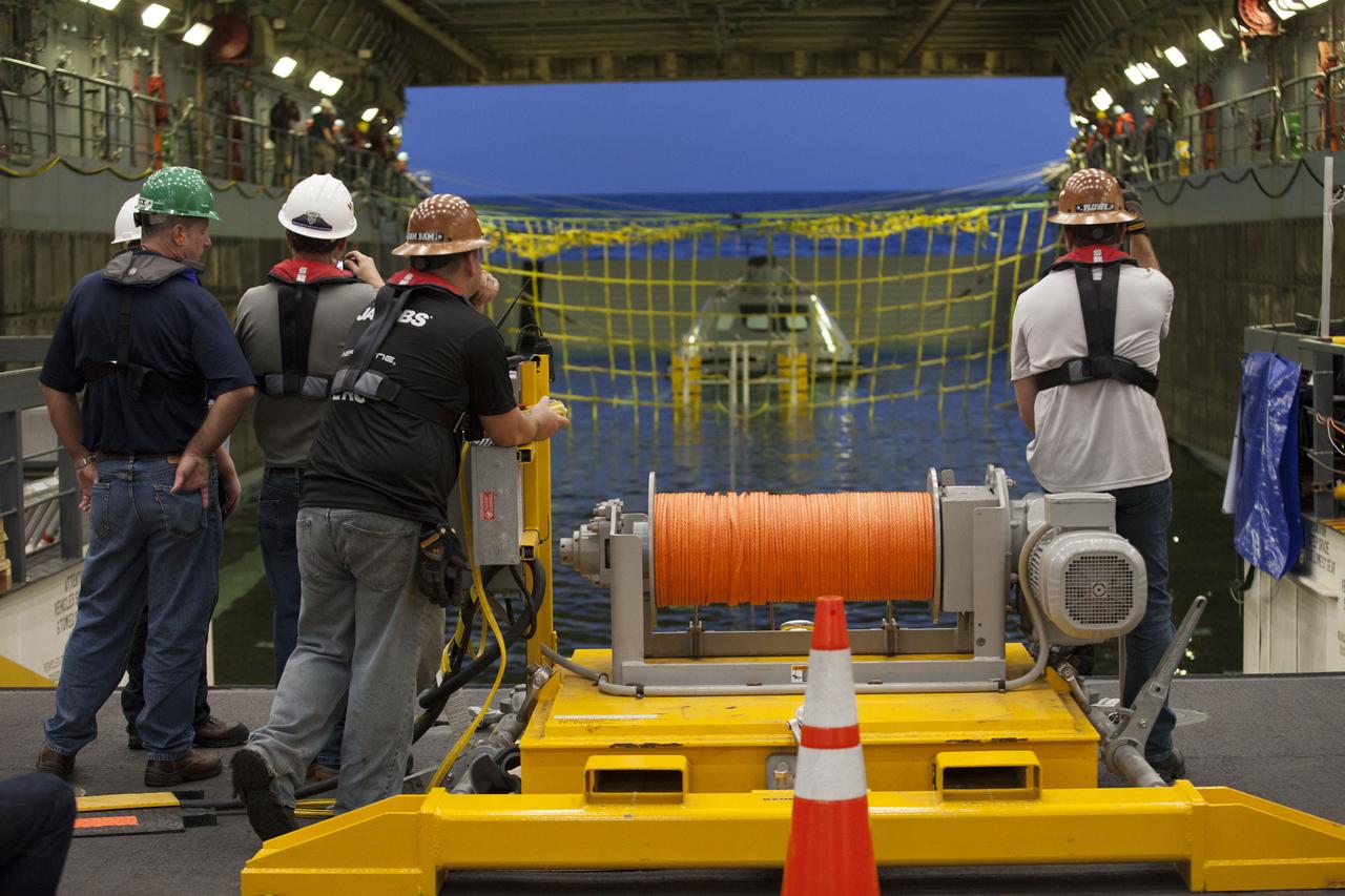 Winch operations team members watch as a test version of the Orion crew module is secured in the flooded well deck of the USS San Diego for the start of Underway Recovery Test 5 in the Pacific Ocean off the coast of California. NASA's Ground Systems Development and Operations Program and the U.S. Navy are conducting a series of tests to prepare for recovery of Orion on its return from deep space missions. The testing will allow the team to demonstrate and evaluate recovery processes, procedures, hardware and personnel in open waters. Orion is the exploration spacecraft designed to carry astronauts to destinations not yet explored by humans, including an asteroid and NASA's Journey to Mars. It will have emergency abort capability, sustain the crew during space travel and provide safe re-entry from deep space return velocities. Orion is scheduled to launch on NASA's Space Launch System in late 2018. For more information, visit http://www.nasa.gov/orion. 