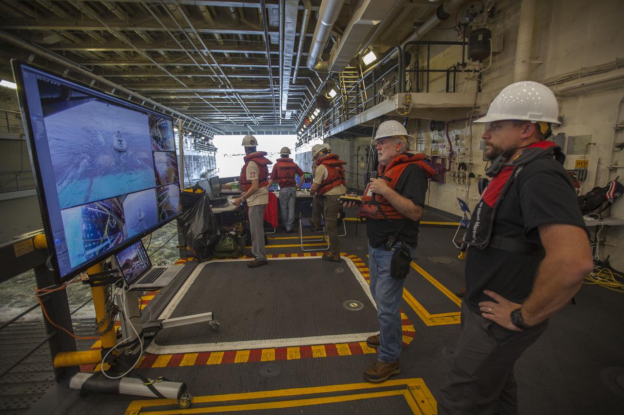 In the well deck of the USS San Diego, recovery team members monitor a portion of Underway Recovery Test 5 in the Pacific Ocean off the coast of California. A test version of the Orion crew module is floating in open waters. NASA's Ground Systems Development and Operations Program and the U.S. Navy are conducting a series of tests using the ship's well deck, the test module, various watercraft and equipment to prepare for recovery of Orion on its return from deep space missions. The test will allow the team to demonstrate and evaluate recovery processes, procedures, hardware and personnel in open waters. Orion is the exploration spacecraft designed to carry astronauts to destinations not yet explored by humans, including an asteroid and NASA's Journey to Mars. It will have emergency abort capability, sustain the crew during space travel and provide safe re-entry from deep space return velocities. Orion is scheduled to launch on NASA's Space Launch System in late 2018. For more information, visit http://www.nasa.gov/orion.