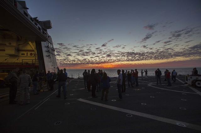 NASA, contractor and U.S. Navy personnel are on the deck of the USS San Diego as the sun sets on the fourth day of Underway Recovery Test 5 in the Pacific Ocean off the coast of California. NASA's Ground Systems Development and Operations Program and the U.S. Navy practiced retrieving and securing a test version of the Orion crew module in the well deck of the ship using tethers and a winch system to prepare for recovery of Orion on its return from deep space missions. The testing will allow the team to demonstrate and evaluate recovery processes, procedures, hardware and personnel in open waters. Orion is the exploration spacecraft designed to carry astronauts to destinations not yet explored by humans, including an asteroid and NASA's Journey to Mars. It will have emergency abort capability, sustain the crew during space travel and provide safe re-entry from deep space return velocities. Orion is scheduled to launch on NASA's Space Launch System in late 2018. For more information, visit http://www.nasa.gov/orion.