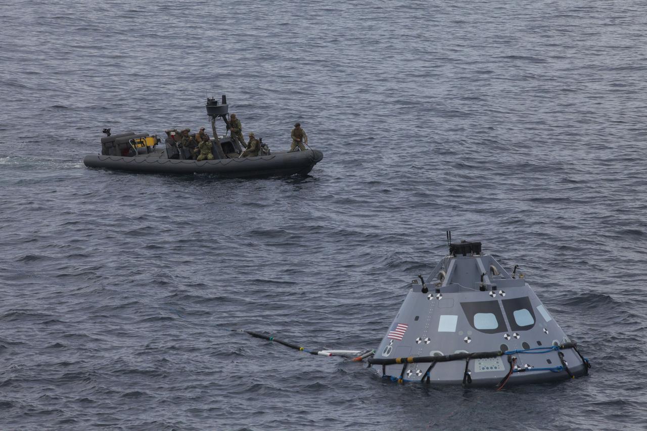 A test version of the Orion crew module floats in the Pacific Ocean during Underway Recovery Test 5 in the Pacific Ocean off the coast of California. Nearby are U.S. Navy divers and other personnel in a rigid hull inflatable boat. NASA's Ground Systems Development and Operations Program and the U.S. Navy are conducting a series of tests using the well deck of the USS San Diego, several watercraft, support equipment and personnel to prepare for recovery of Orion on its return from deep space missions. The testing will allow the team to demonstrate and evaluate recovery processes, procedures, hardware and personnel in open waters. Orion is the exploration spacecraft designed to carry astronauts to destinations not yet explored by humans, including an asteroid and NASA's Journey to Mars. It will have emergency abort capability, sustain the crew during space travel and provide safe re-entry from deep space return velocities. Orion is scheduled to launch on NASA's Space Launch System in late 2018. For more information, visit http://www.nasa.gov/orion. 