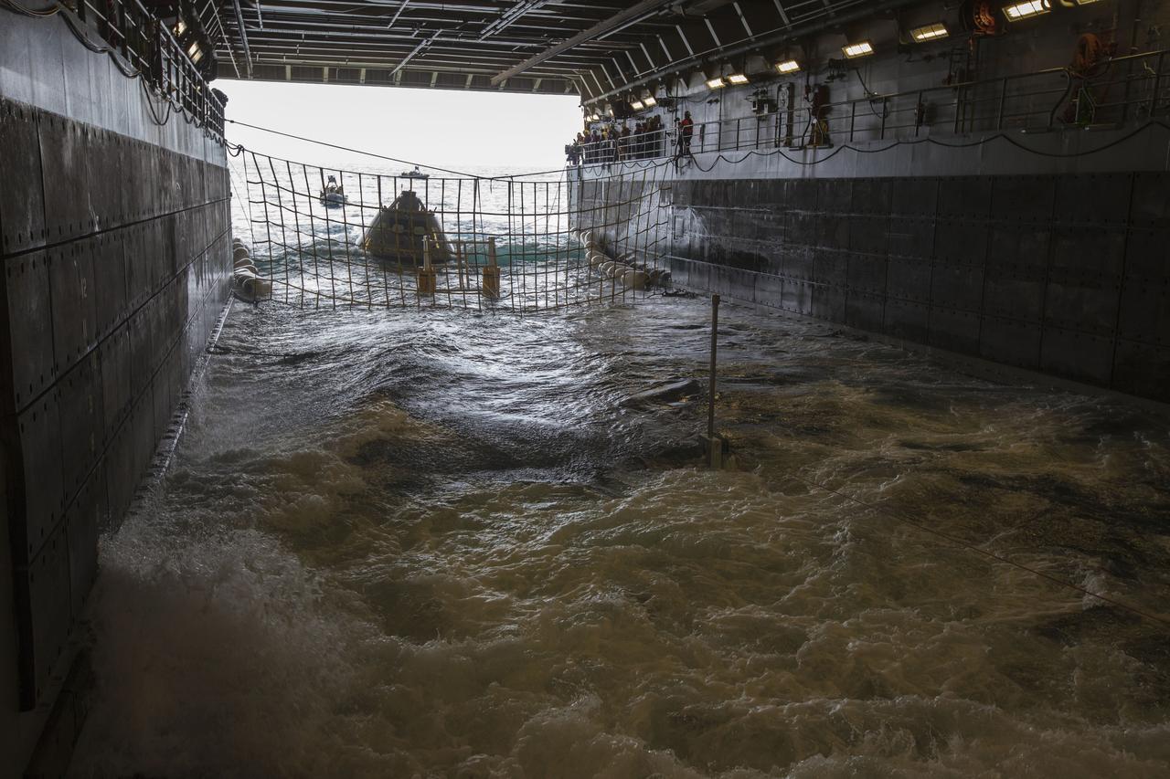 Members of the recovery team watch as the test version of the Orion crew module is guided into the flooded well deck of the USS San Diego during Underway Recovery Test 5 in the Pacific Ocean off the coast of California. NASA's Ground Systems Development and Operations Program and the U.S. Navy are conducting a series of tests using the ship's well deck, the test module, various watercraft and equipment to prepare for recovery of Orion on its return from deep space missions. The testing will allow the team to demonstrate and evaluate recovery processes, procedures, hardware and personnel in open waters. Orion is the exploration spacecraft designed to carry astronauts to destinations not yet explored by humans, including an asteroid and NASA's Journey to Mars. It will have emergency abort capability, sustain the crew during space travel and provide safe re-entry from deep space return velocities. Orion is scheduled to launch on NASA's Space Launch System in late 2018. For more information, visit http://www.nasa.gov/orion.