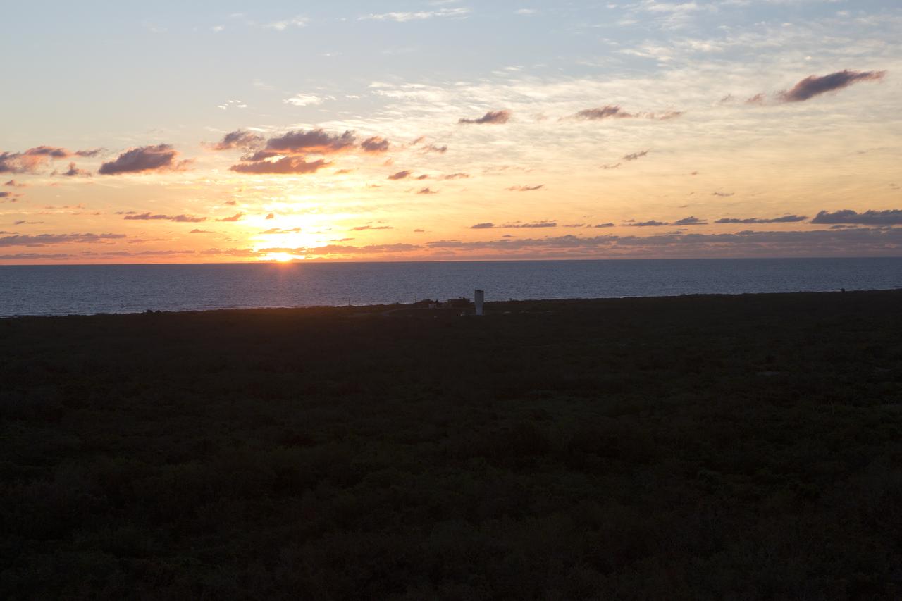 A colorful sunrise fills the early morning sky as the United Launch Alliance Atlas V Centaur second stage is transported along the beach road to the Vertical Integration Facility at Space Launch Complex 41 at Cape Canaveral Air Force Station in Florida. The Geostationary Operational Environmental Satellite (GOES-R) will launch aboard the Atlas V rocket in November. GOES-R is the first satellite in a series of next-generation NOAA GOES Satellites. 