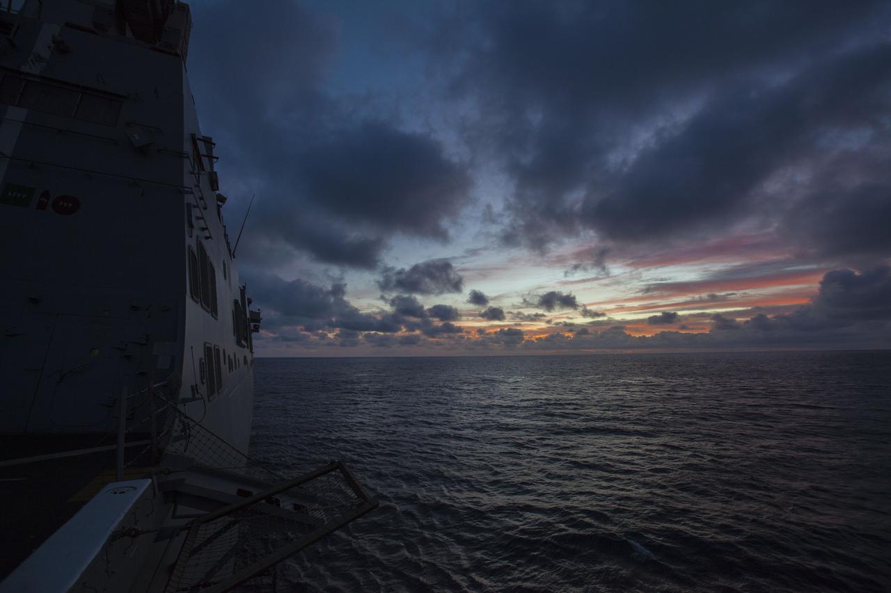 A sunrise colors the sky as another day of Underway Recovery Test 5 begins on the USS San Diego in the Pacific Ocean off the coast of California. NASA's Ground Systems Development and Operations Program and the U.S. Navy are practicing recovery techniques using the well deck of the ship and a test version of the Orion crew module to prepare for recovery of Orion on its return from deep space missions. The testing will allow the team to demonstrate and evaluate recovery processes, procedures, hardware and personnel in open waters. Orion is the exploration spacecraft designed to carry astronauts to destinations not yet explored by humans, including an asteroid and NASA's Journey to Mars. It will have emergency abort capability, sustain the crew during space travel and provide safe re-entry from deep space return velocities. Orion is scheduled to launch on NASA's Space Launch System in late 2018. For more information, visit http://www.nasa.gov/orion. 