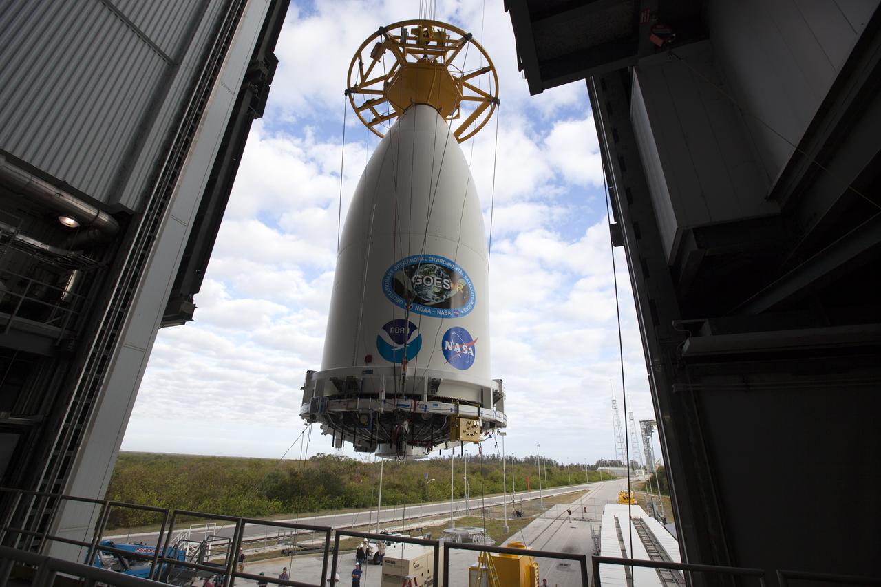A view from high up inside the Vertical Integration Facility at Space Launch Complex 41 at Cape Canaveral Air Force Station in Florida. A crane lifts the payload fairing containing NOAA's Geostationary Operational Environmental Satellite (GOES-R) for mating to the United Launch Alliance Atlas V Centaur upper stage. The satellite will launch aboard the Atlas V rocket in November. GOES-R is the first satellite in a series of next-generation NOAA GOES Satellites.