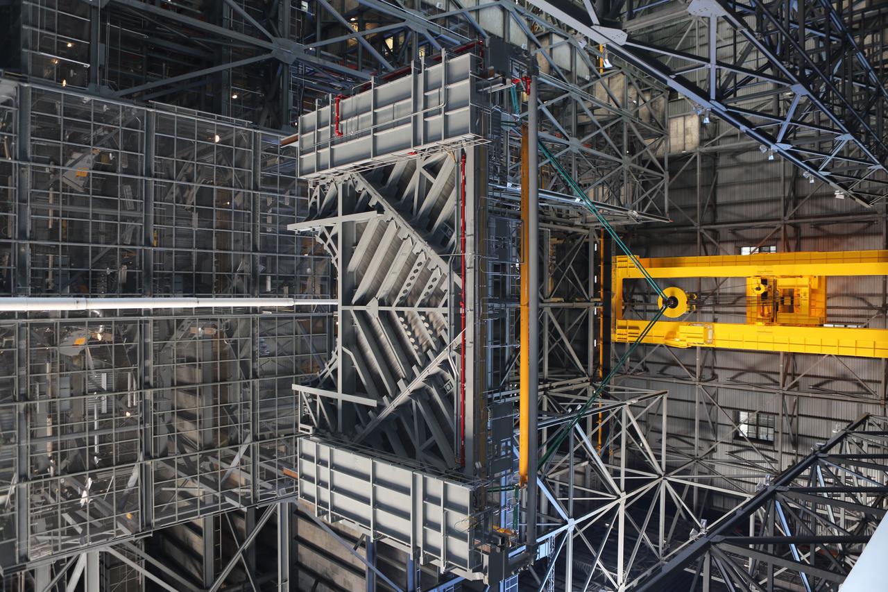 A heavy-lift crane lifts the second half of the C-level work platforms, C north, for NASA’s Space Launch System (SLS) rocket, high up from the transfer aisle of the Vehicle Assembly Building (VAB) at NASA's Kennedy Space Center in Florida. The C platform will be moved into High Bay 3 for installation on the north side of High Bay 3. The C platforms are the eighth of 10 levels of work platforms that will surround and provide access to the SLS rocket and Orion spacecraft for Exploration Mission 1. In view below Platform C are several of the previously installed platforms. The Ground Systems Development and Operations Program is overseeing upgrades and modifications to VAB High Bay 3, including installation of the new work platforms, to prepare for NASA’s Journey to Mars. 