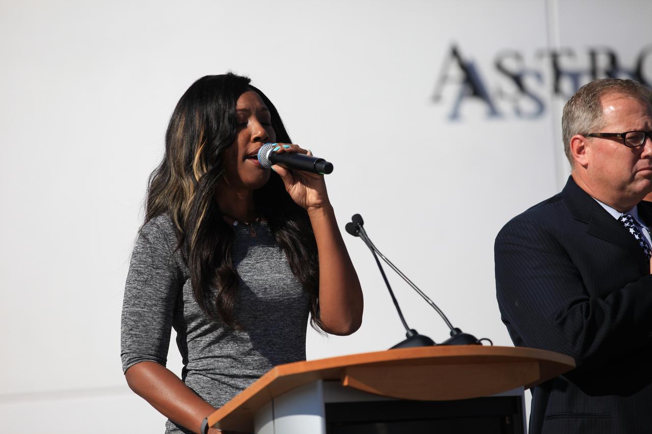 During the grand opening of the Heroes and Legends attraction at the Kennedy Space Center Visitor Complex, the national anthem was performed by Carmen Harrell. Therrin Protze, chief operating officer of the visitor complex is seen on the right. The new facility includes the U.S. Astronaut Hall of Fame and looks back to the pioneering efforts of Mercury, Gemini and Apollo. It sets the stage by providing the background and context for space exploration and the legendary men and women who pioneered the nation's journey into space.