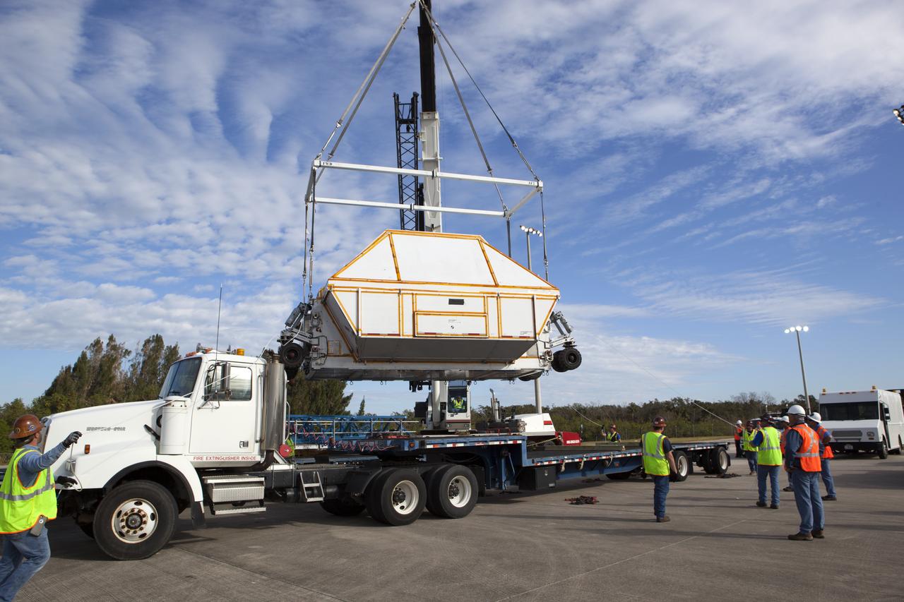 After arriving at the Shuttle Landing Facility operated by Space Florida at NASA's Kennedy Space Center in Florida, the agency's Super Guppy aircraft was opened and the container holding the Orion crew module structural test article (STA) was offloaded. A crane is used to lower the container for placement on a transporter. The test article will be moved to the Neil Armstrong Operations and Checkout Building high bay for further testing. The Orion spacecraft will launch atop NASA’s Space Launch System rocket on EM-1, its first deep space mission, in late 2018.