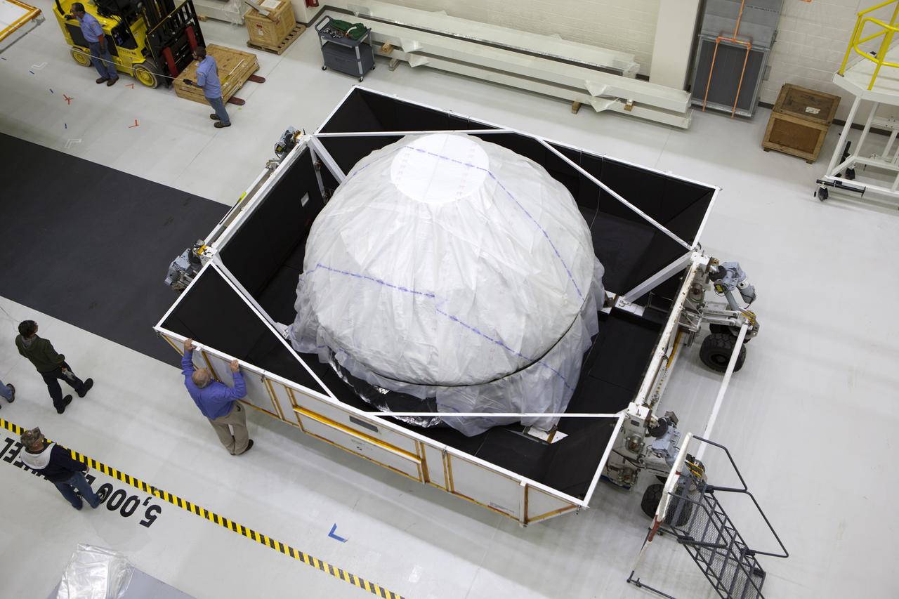 Inside the Neil Armstrong Operations and Checkout Building high bay at NASA's Kennedy Space Center in Florida, the cover has been removed from the container holding the Orion crew module structural test article (STA). The STA arrived aboard NASA's Super Guppy aircraft at the Shuttle Landing Facility operated by Space Florida. The test article was moved inside the facility's high bay for further testing. The Orion spacecraft will launch atop NASA’s Space Launch System rocket on EM-1, its first deep space mission, in late 2018.