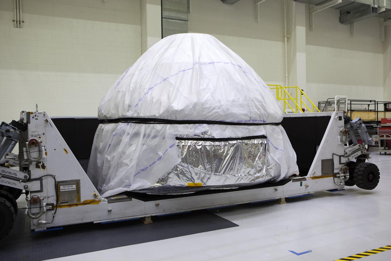 Inside the Neil Armstrong Operations and Checkout Building high bay at NASA's Kennedy Space Center in Florida, the cover has been removed from the container holding the Orion crew module structural test article (STA). The STA arrived aboard NASA's Super Guppy aircraft at the Shuttle Landing Facility operated by Space Florida. The test article was moved inside the facility's high bay for further testing. The Orion spacecraft will launch atop NASA’s Space Launch System rocket on EM-1, its first deep space mission, in late 2018.
